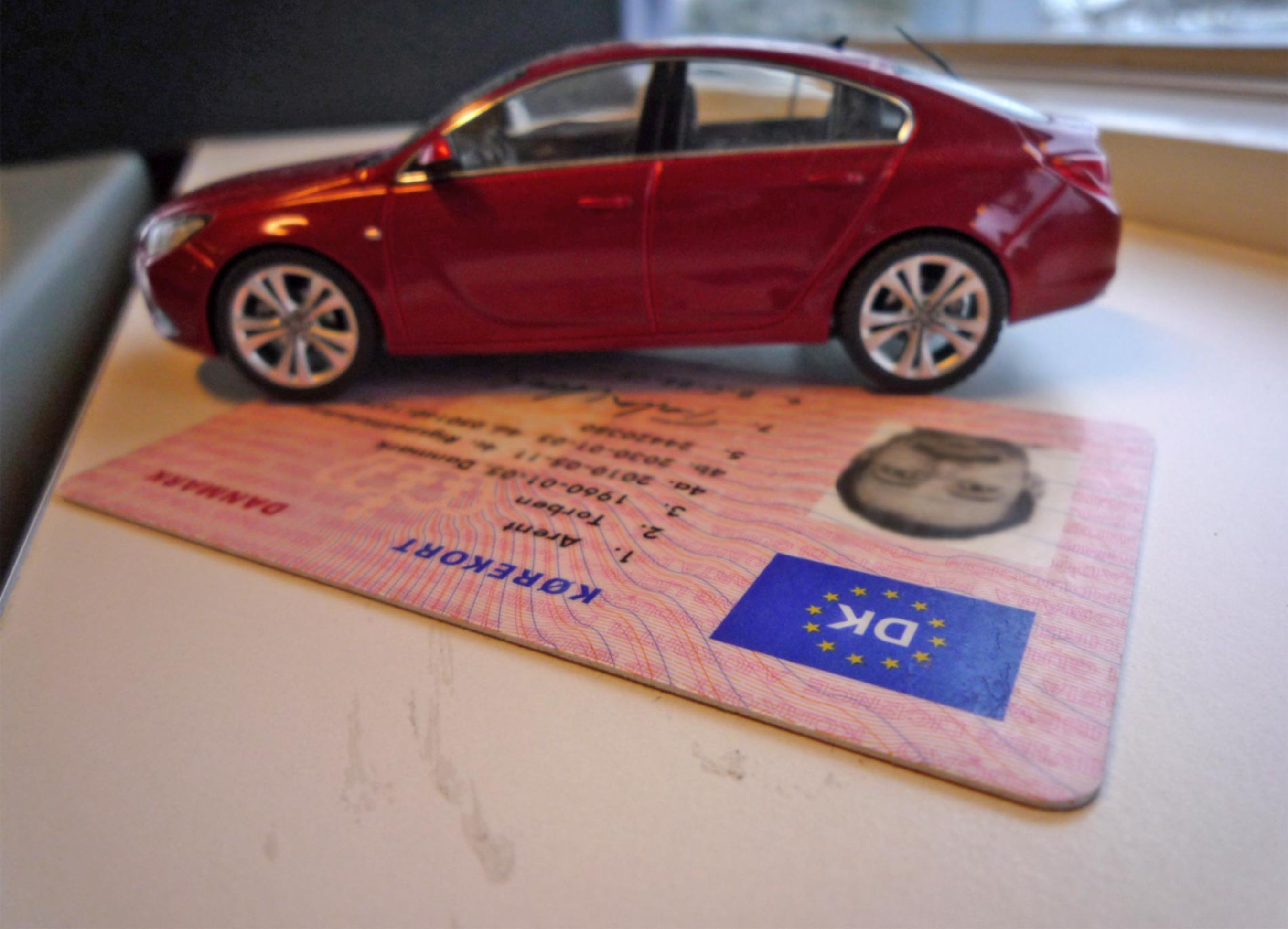 Nærbillede af kørekort med modelbil ovenpå.