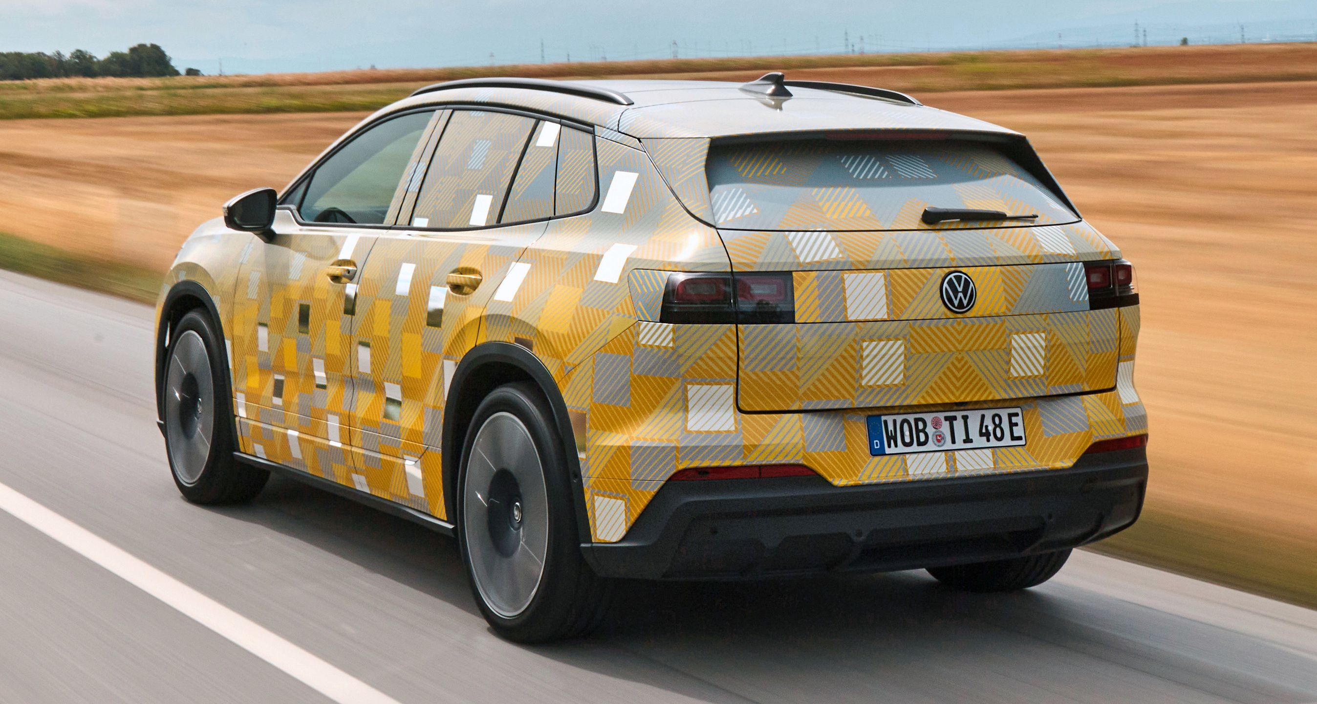 Kamufleret, gul VW ID. Tiguan kørende set bagfra.