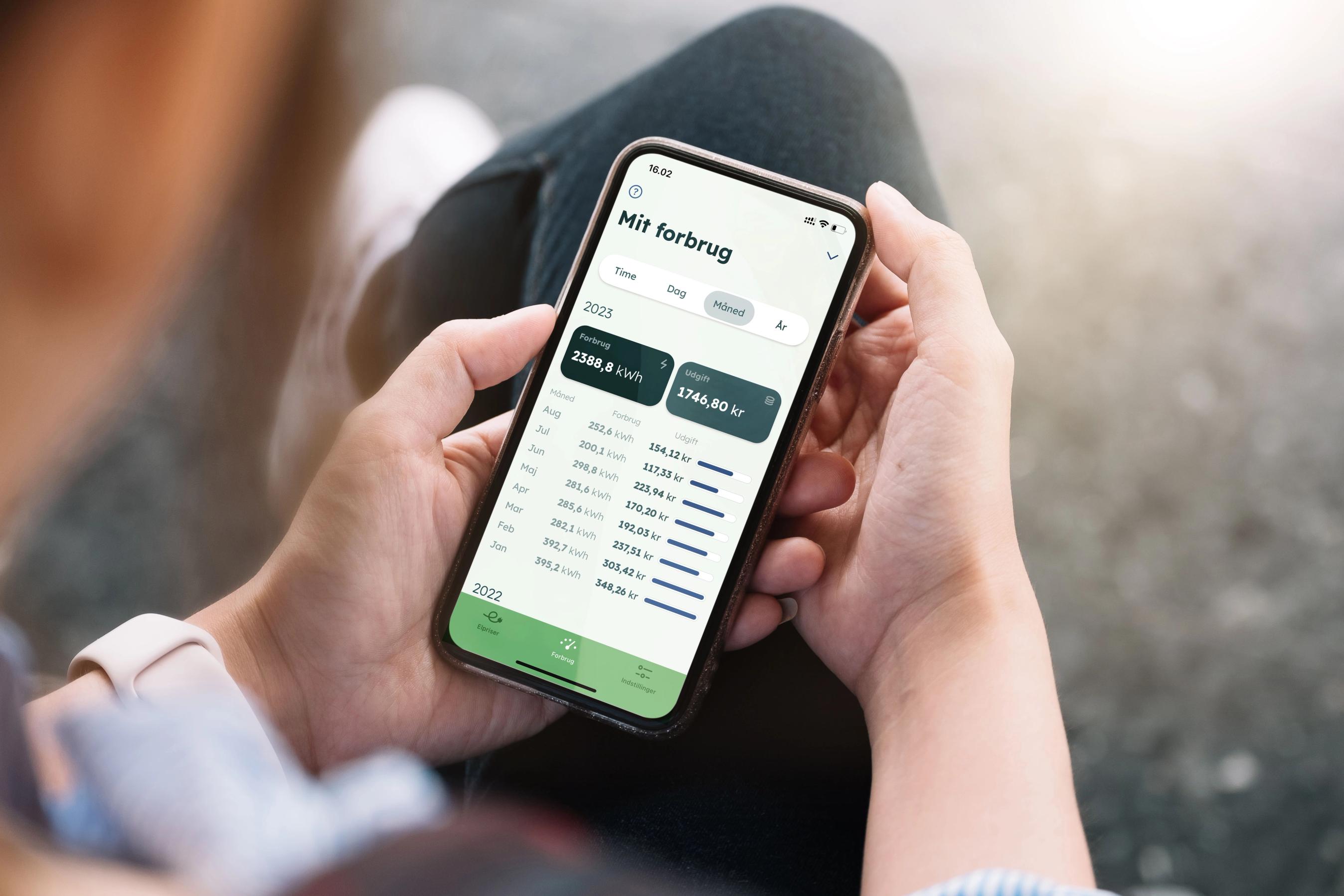 Mand sidder med telefon i hånden der viser strømforbrug med Ellos app