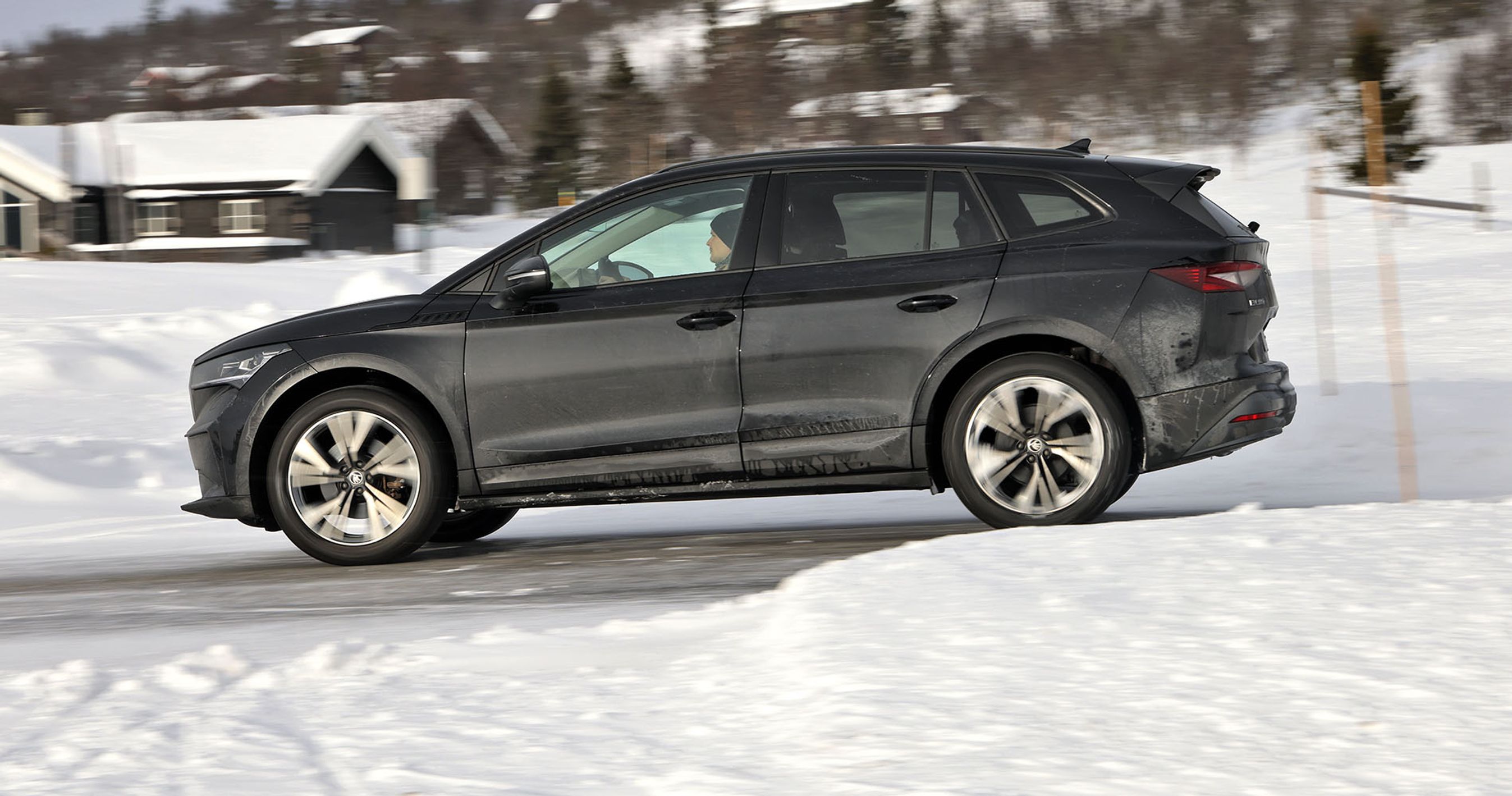 En Skoda Enyaq elbil set fra siden kører på en snedækket vej