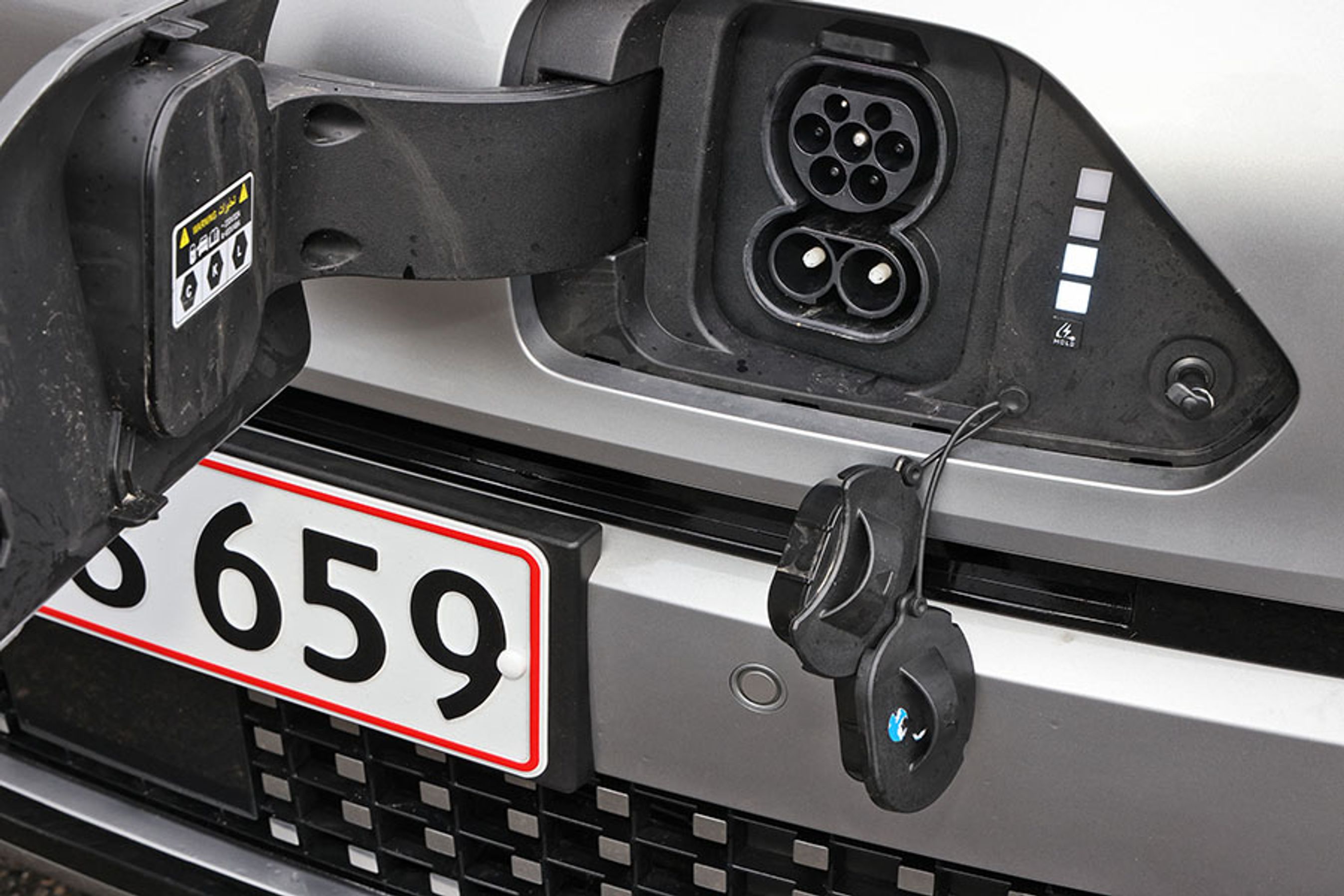 Ladestikket er placeret i fronten, og bag klappen er der to gummipropper, der lidt besværligt skal fjernes før opladningen. Hjemme lader bilen med 11 kW (3 faser) og på farten med op til 102 kW.