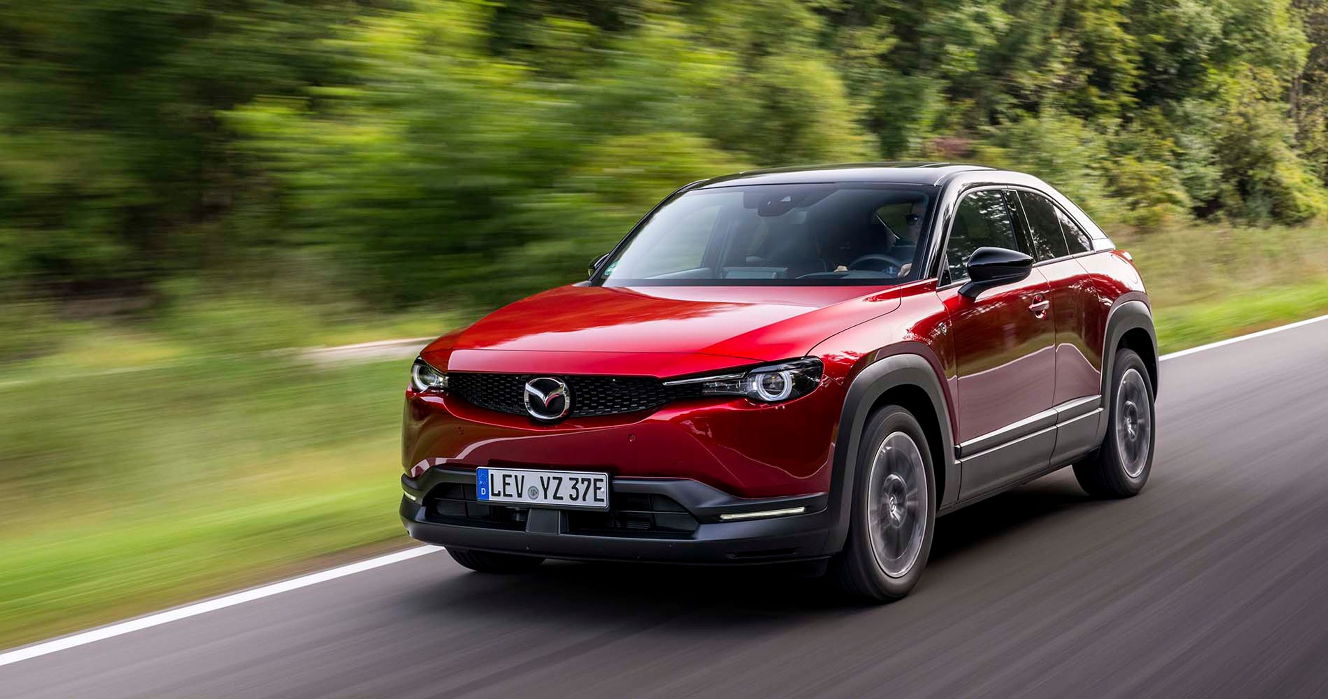 En rød Mazda MX-30 kører på en landevej i fuld fart