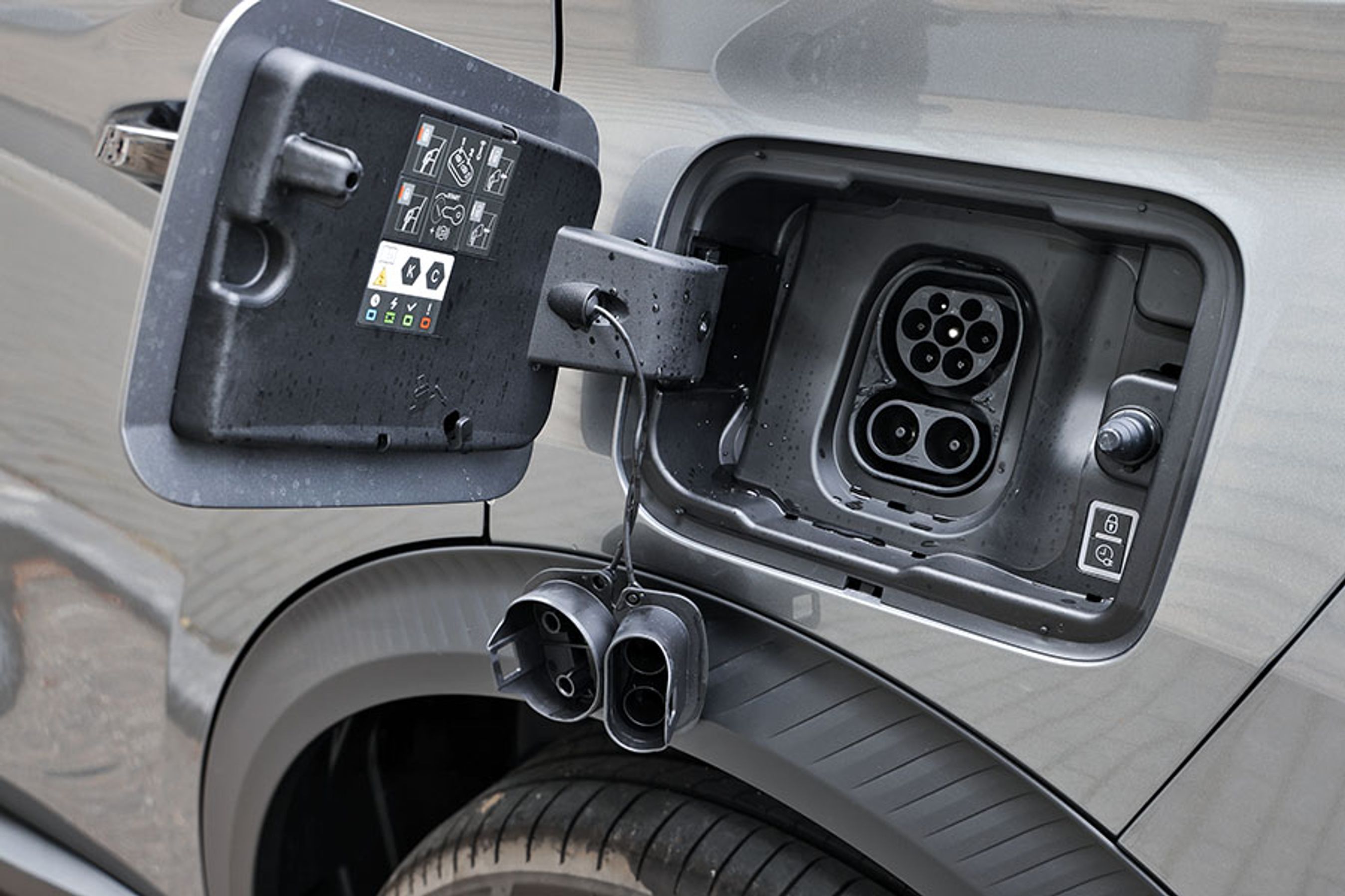 Ladestikket er placeret ved vestre baghjul. Der er – lidt irriterende – gummipropper ved begge stik. På farten lader bilen med op til 100 kW og hjemme med 11 kW via en ladeboks med tre faser.