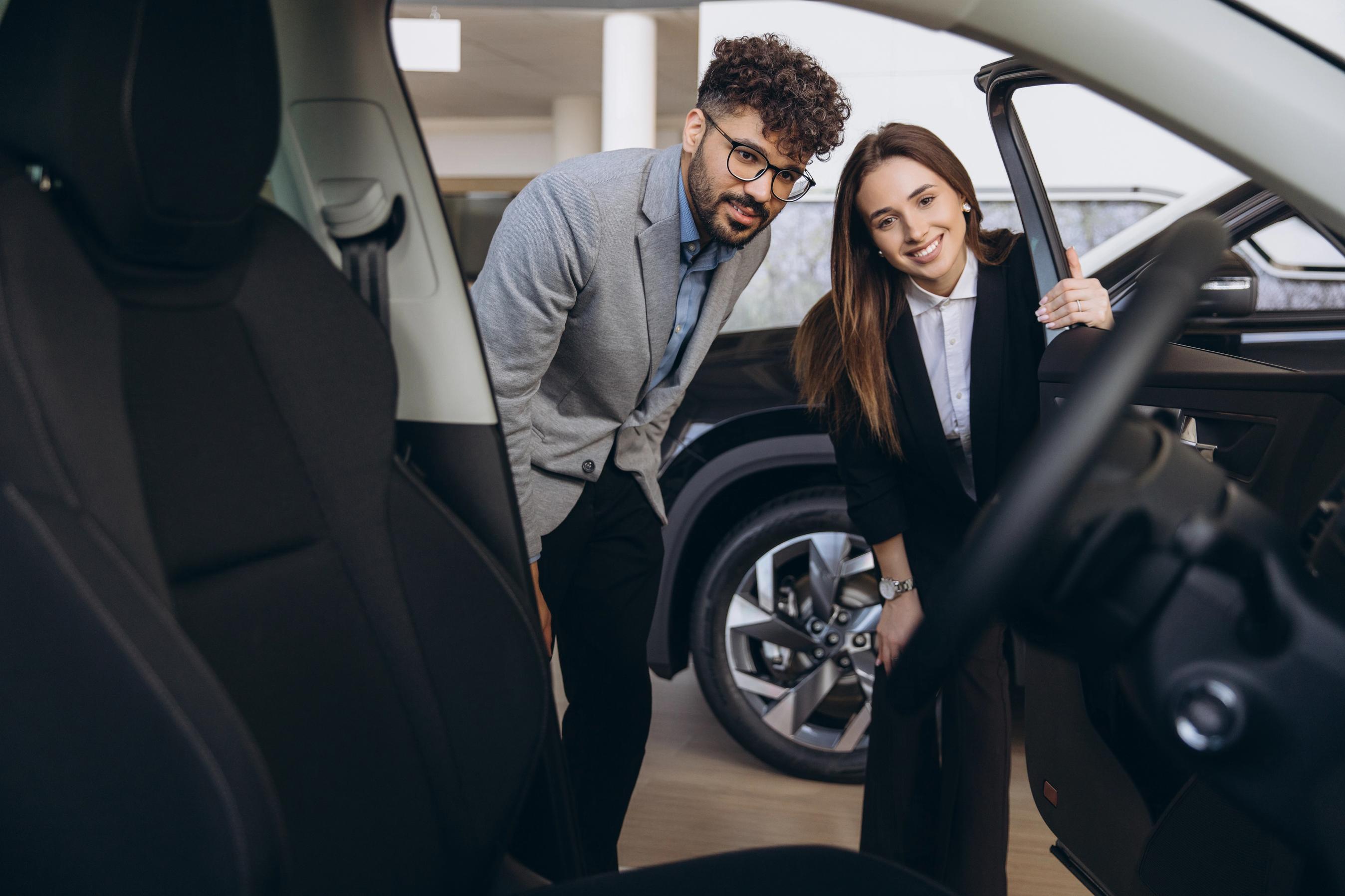 Mand og kvinde kigger på bil hos bilforhandler