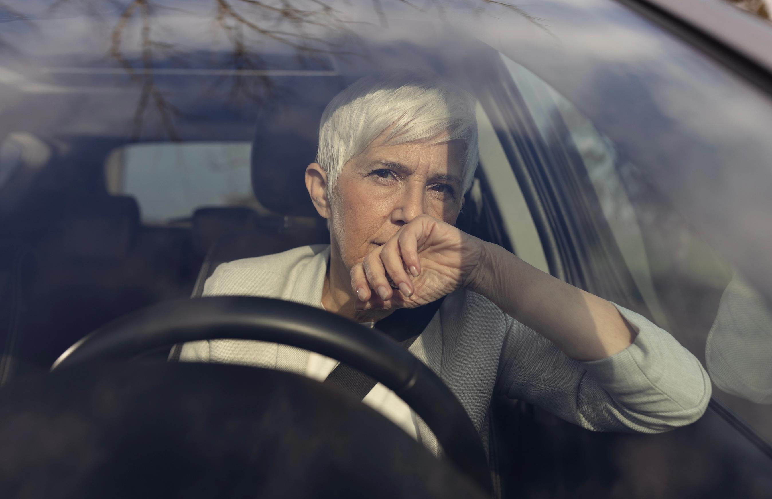 Kvinde sidder i bilen og kigger ud af forruden.