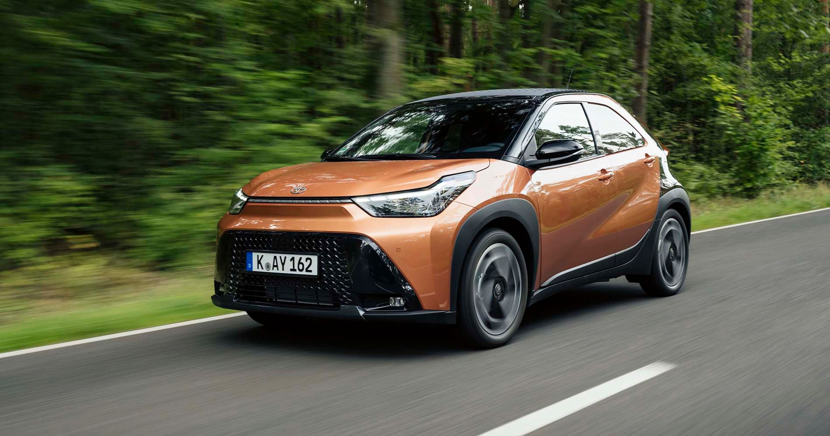 Toyota Aygo X set skråt forfra, mens den kører med træer i baggrunden
