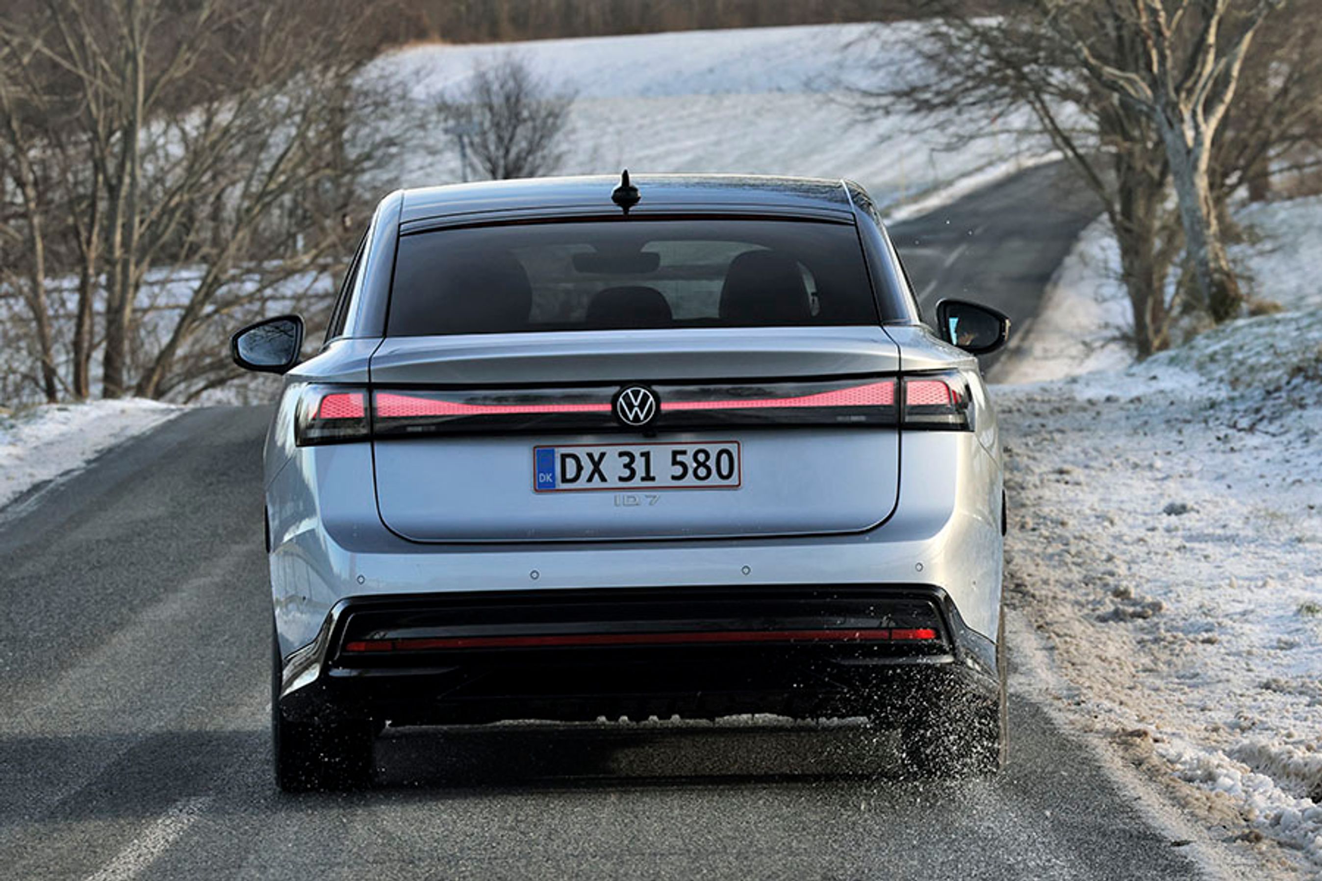 VW ID.7 set direkte bagfra, mens den kører på vej i snelandskab