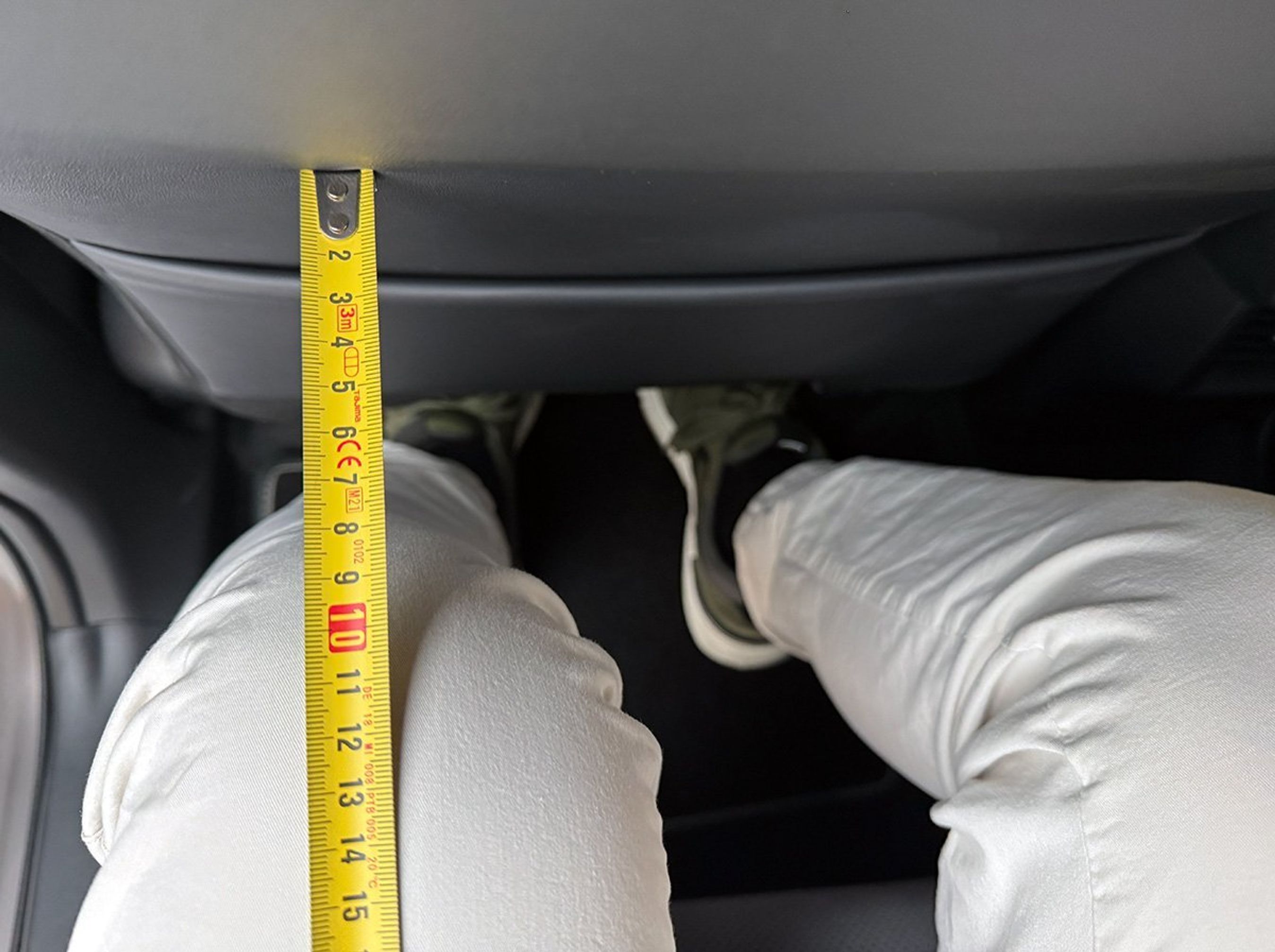 Målebånd og knæ ved bilbagsæde.