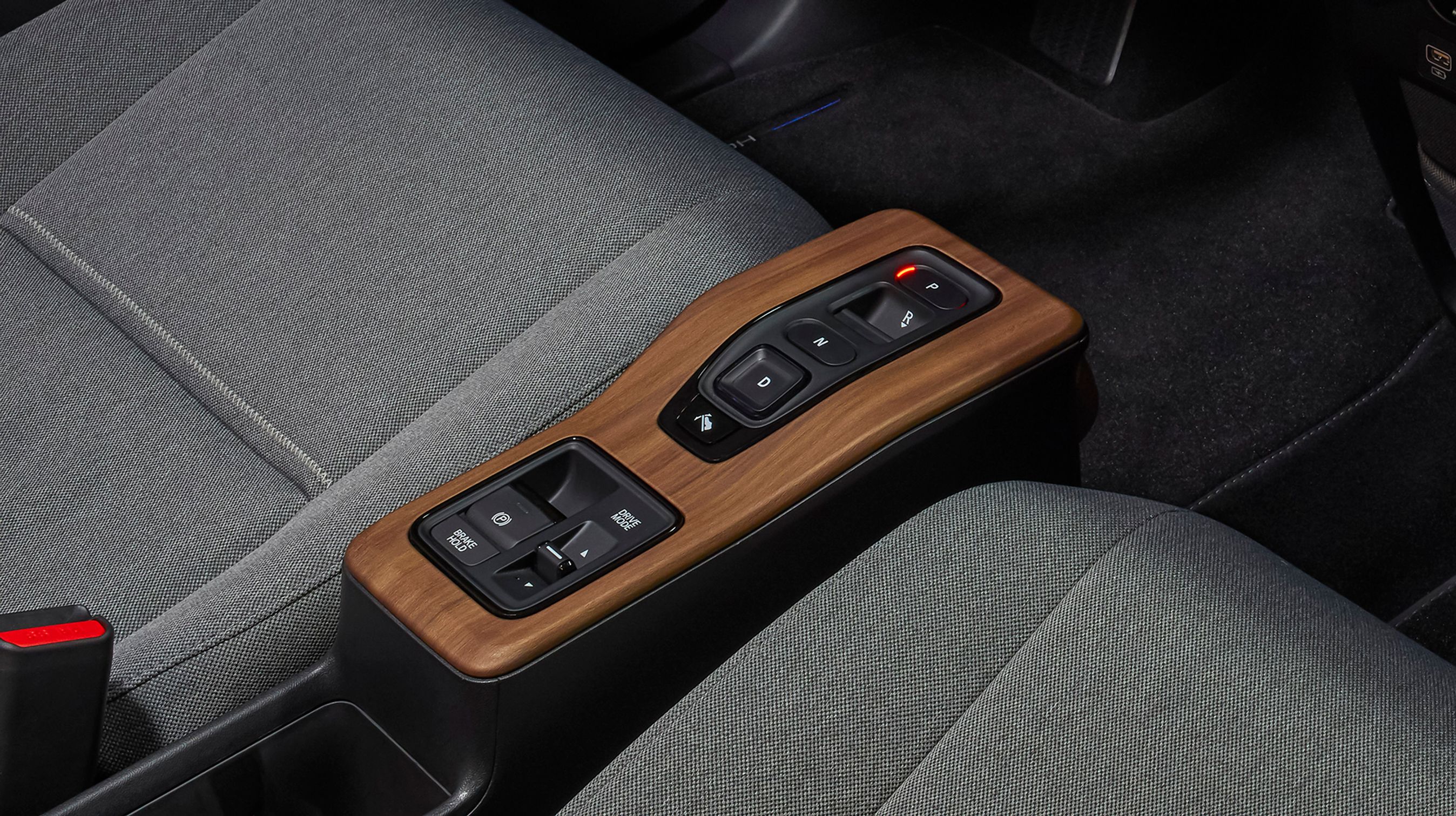 Der er ingen gearstang i Honda e. I stedet findes et par knapper mellem forsæderne, hvorfra man bestemmer kørselsretningen. Under klimaanlægget findes flere USB-stik og et 230-Volt strømudtag.