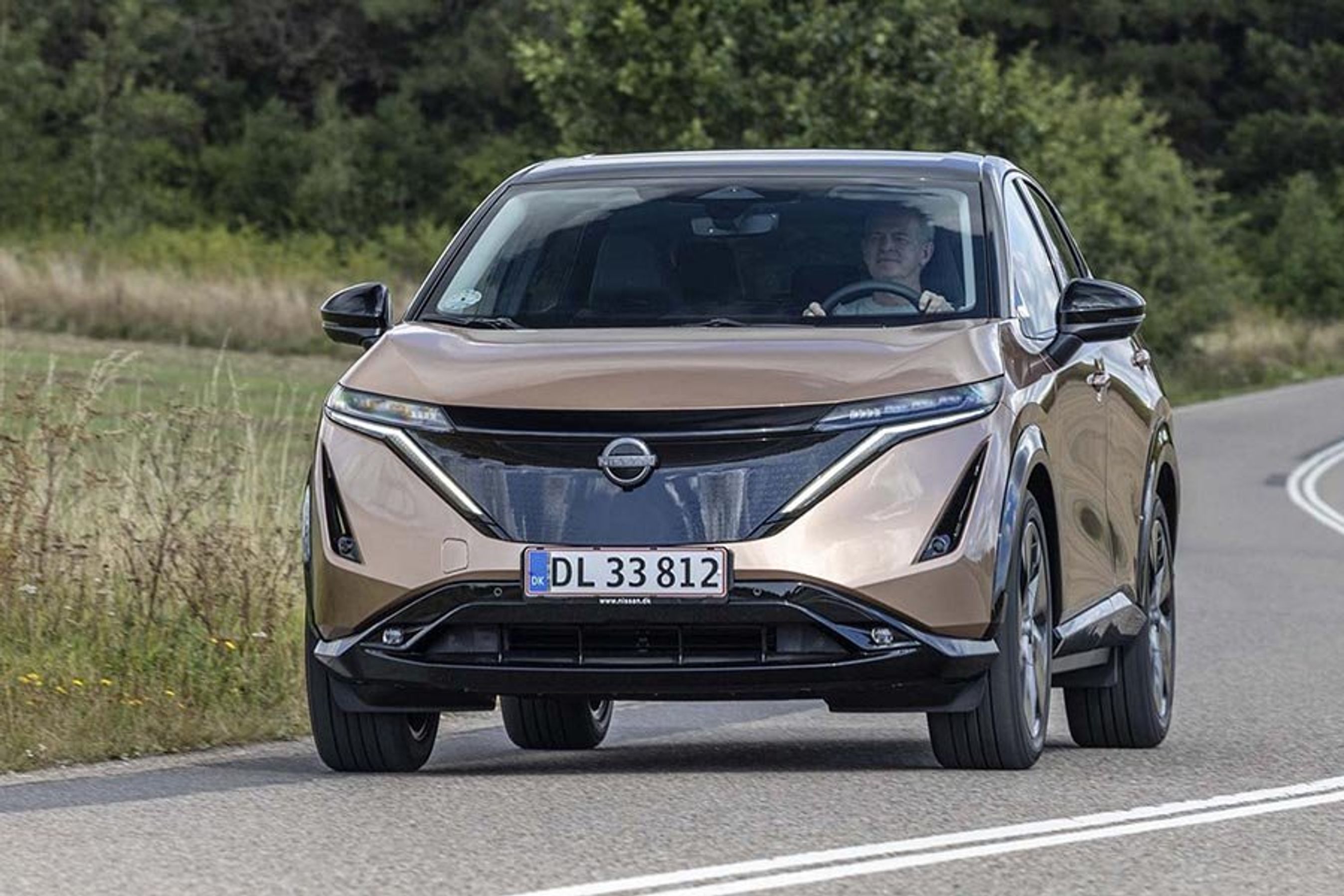 Nissan Ariya kører på en landevej i Danmark.