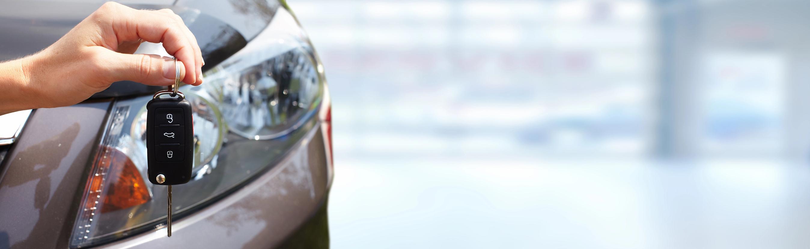 Hånd holder bilnøgle foran bil