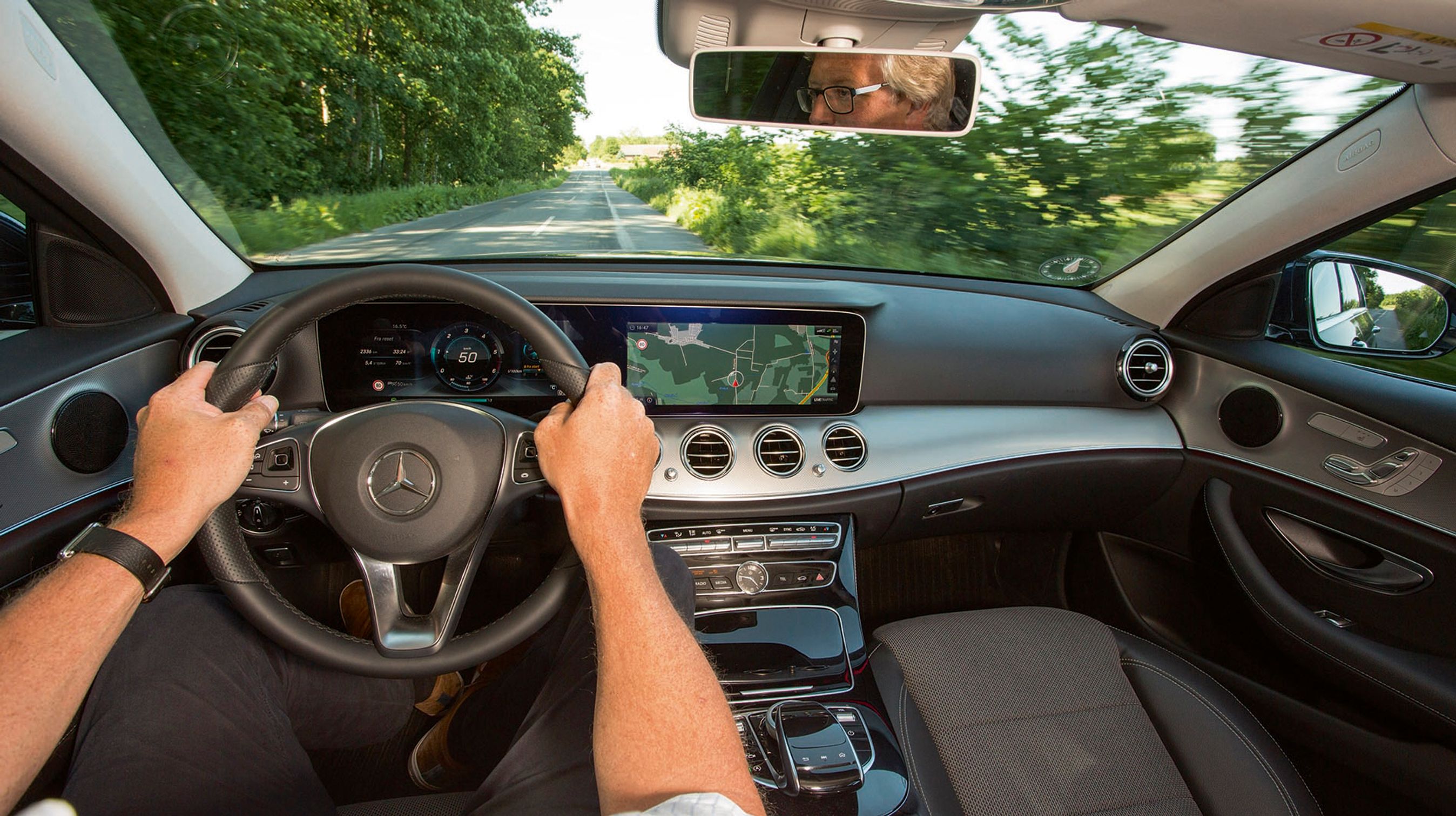 Førerpladsen i den nye E-klasse er moderne og avanceret. Den store skærm, der løber i det meste af instrumentbordets bredde, er ekstraudstyr, men kan varmt anbefales. Her kan man selv bestemme instrumenternes udseende, og til højre kan man styre navigationsanlæg, radio og en stor del af bilens mange smarte funktioner.