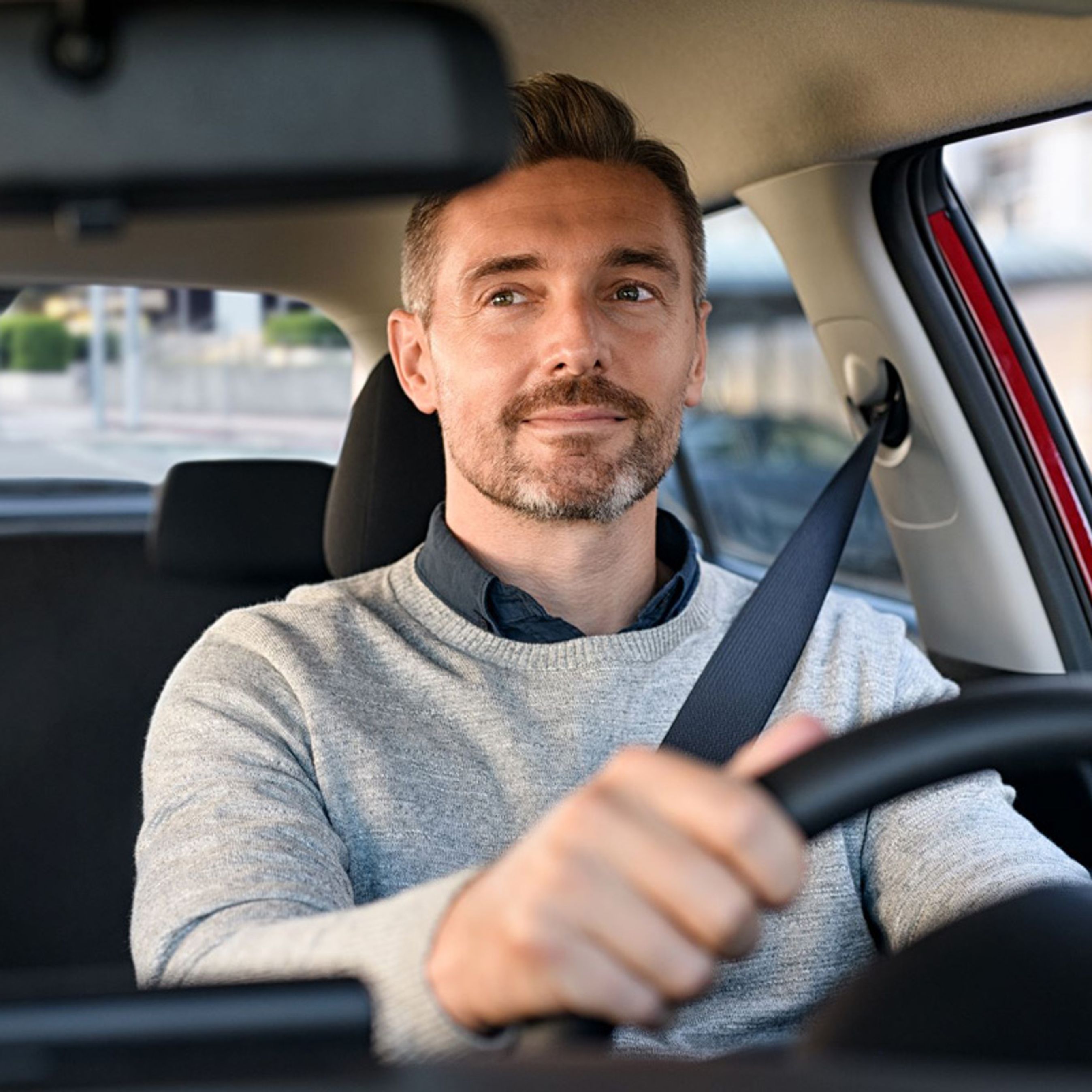 Mand kører i bil og kigger i bakspejlet