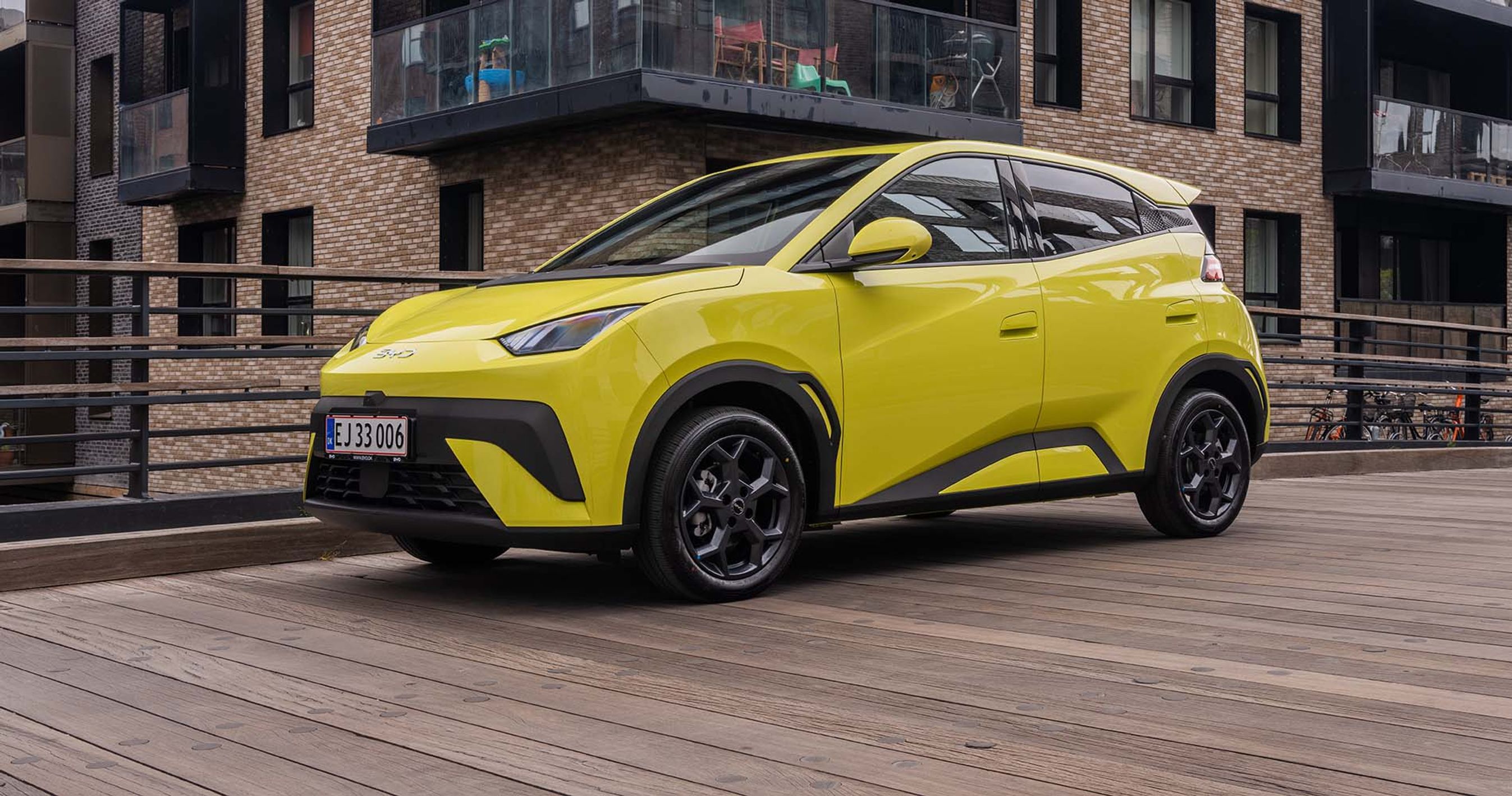 Gul BYD Dolphin Surf holder på træbro i by