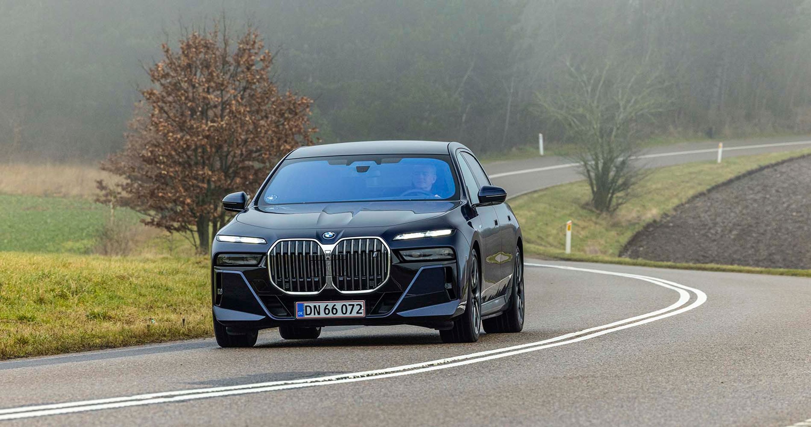 BMW i7 kører på snoet vej i tåget vejr