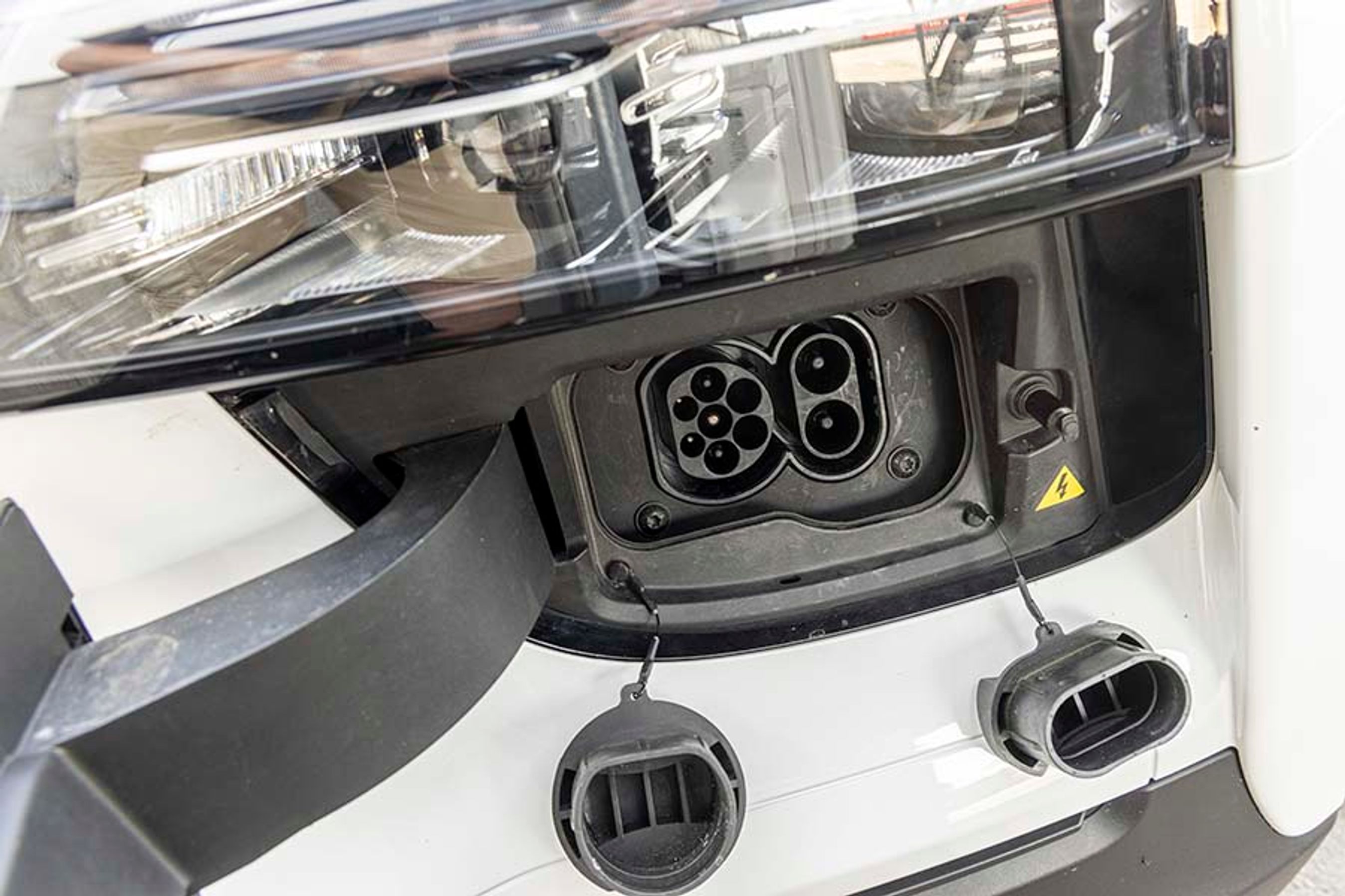 Ladeporten er placeret i fronten ved venstre forlygte. Man skal ned i knæ for at fjerne plastpropperne, og vi savner både lys, kontrollys og en separat udløserknap. Hjemme kan de nye udgaver lade med tre faser og 11 kW, og på farten kan man DC-lade med op til 90 kW.