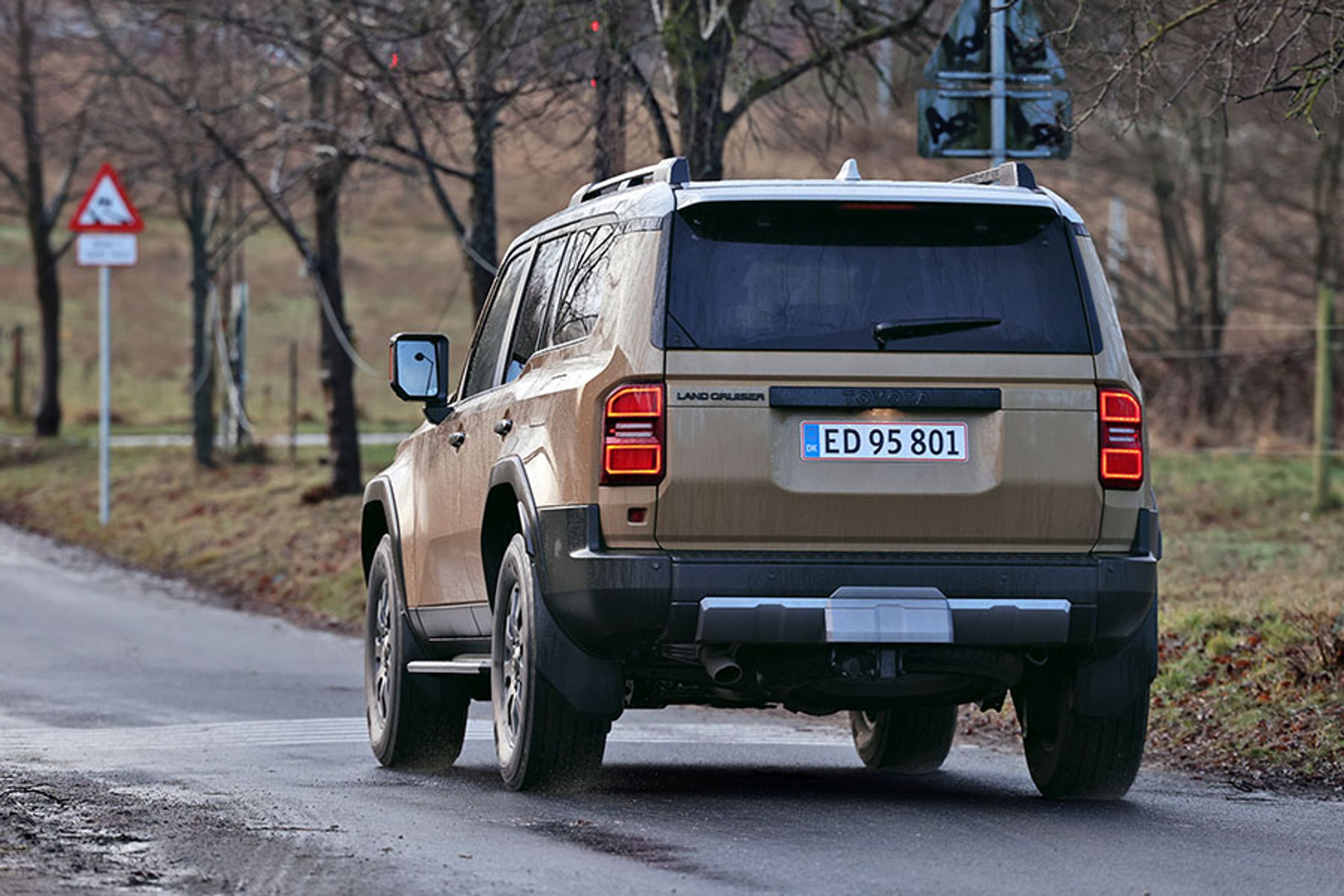 En Toyota Land Cruiser set skråt bagfra kører på landevej 