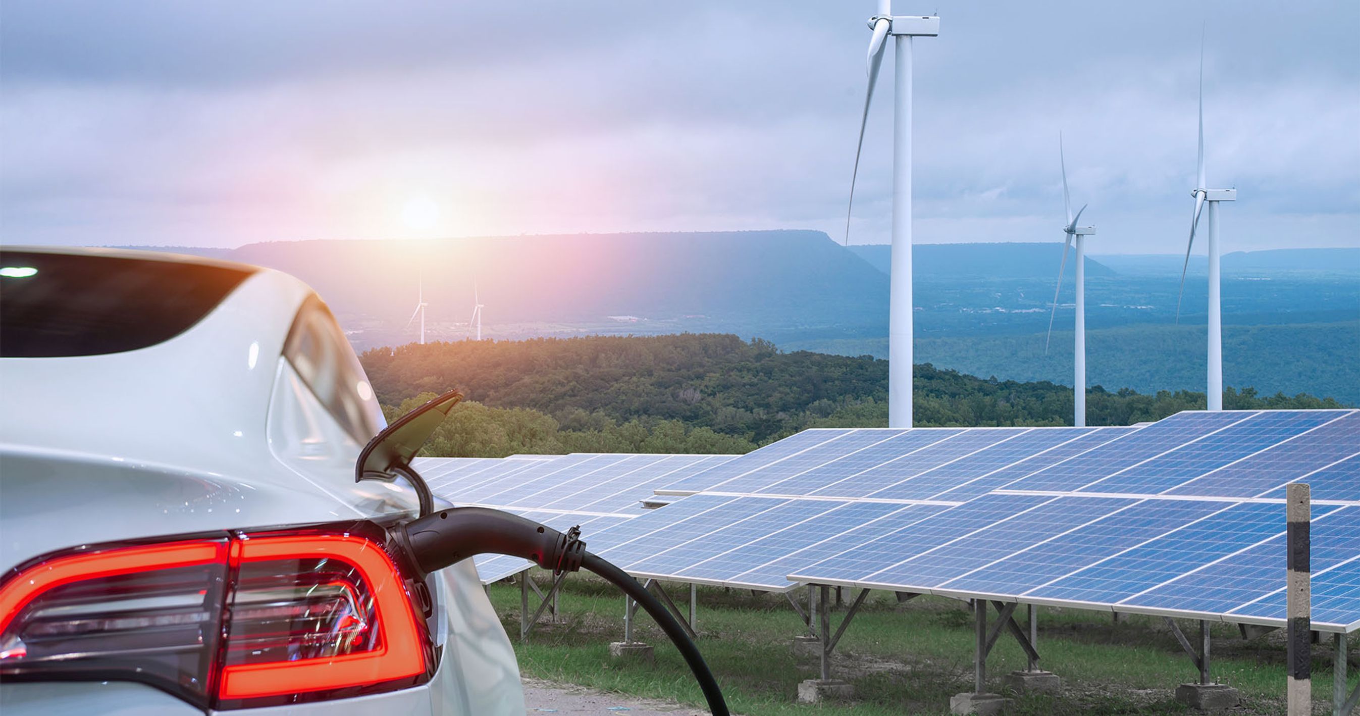 Elbil lader. I baggrunden er der vindmøller og solceller