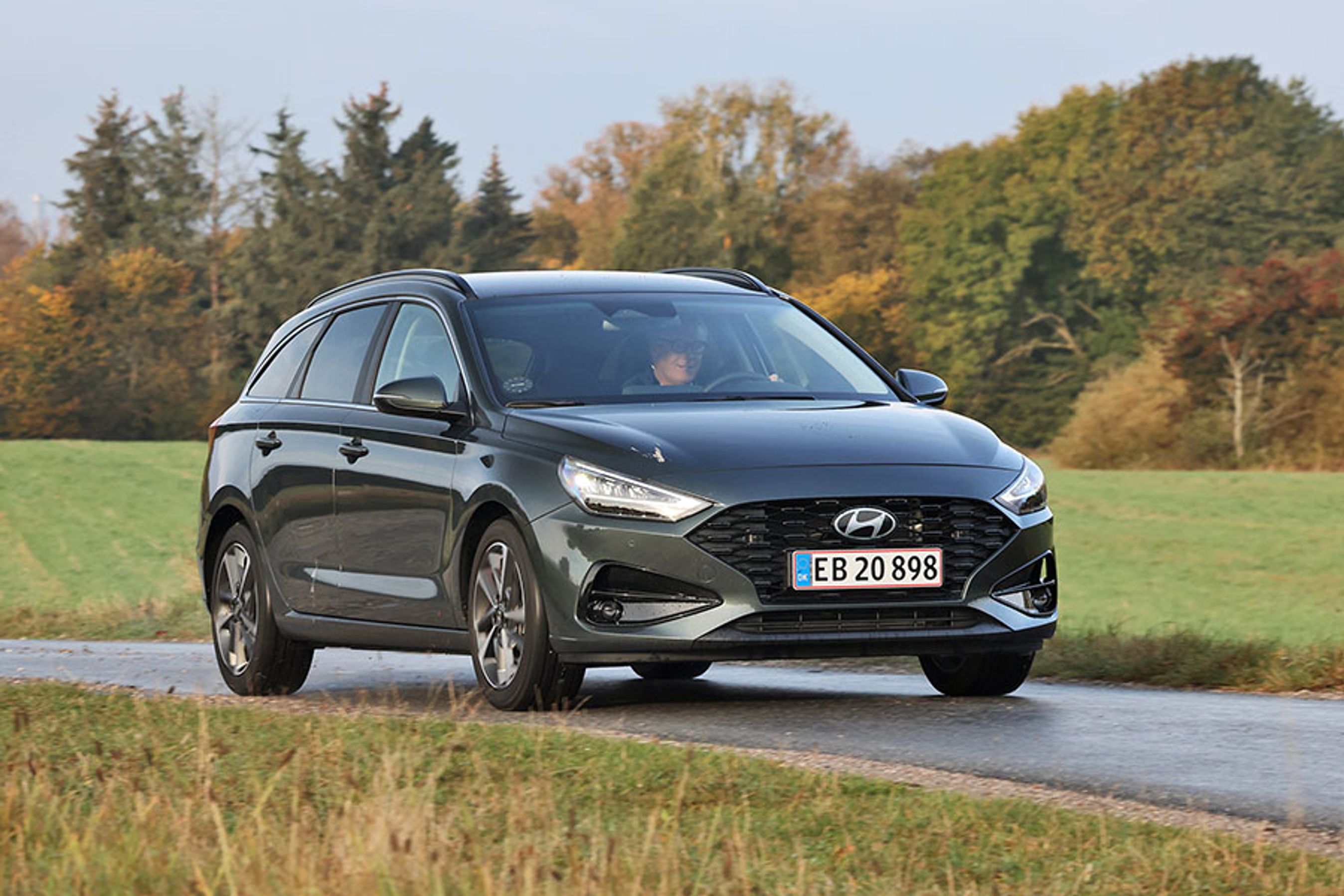 En sort Hyundai i30 stationcar set forfra, mens den kører på en landevej med græs i baggrunden