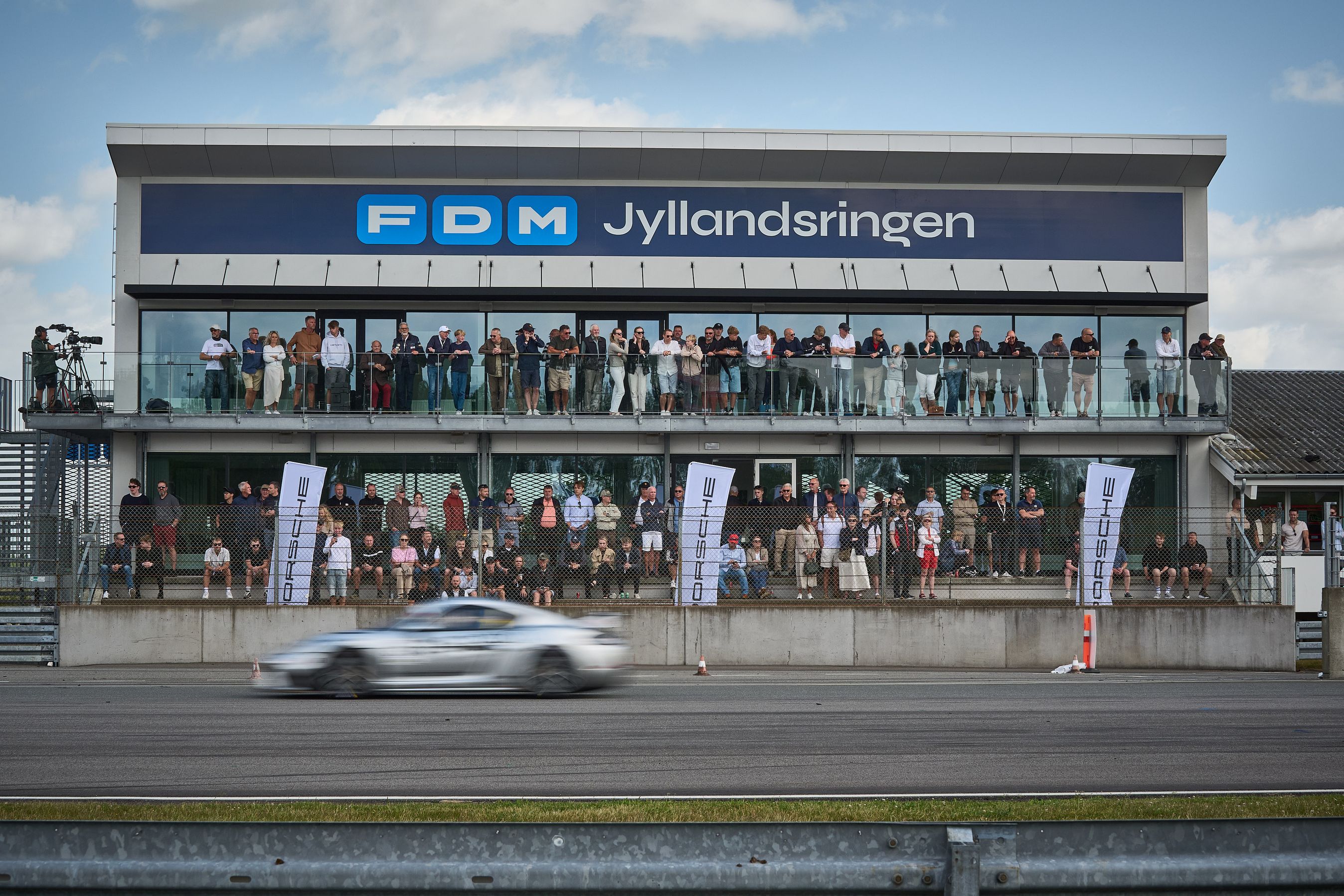 Racerbil kører forbi tribune på FDM Jyllandsringen