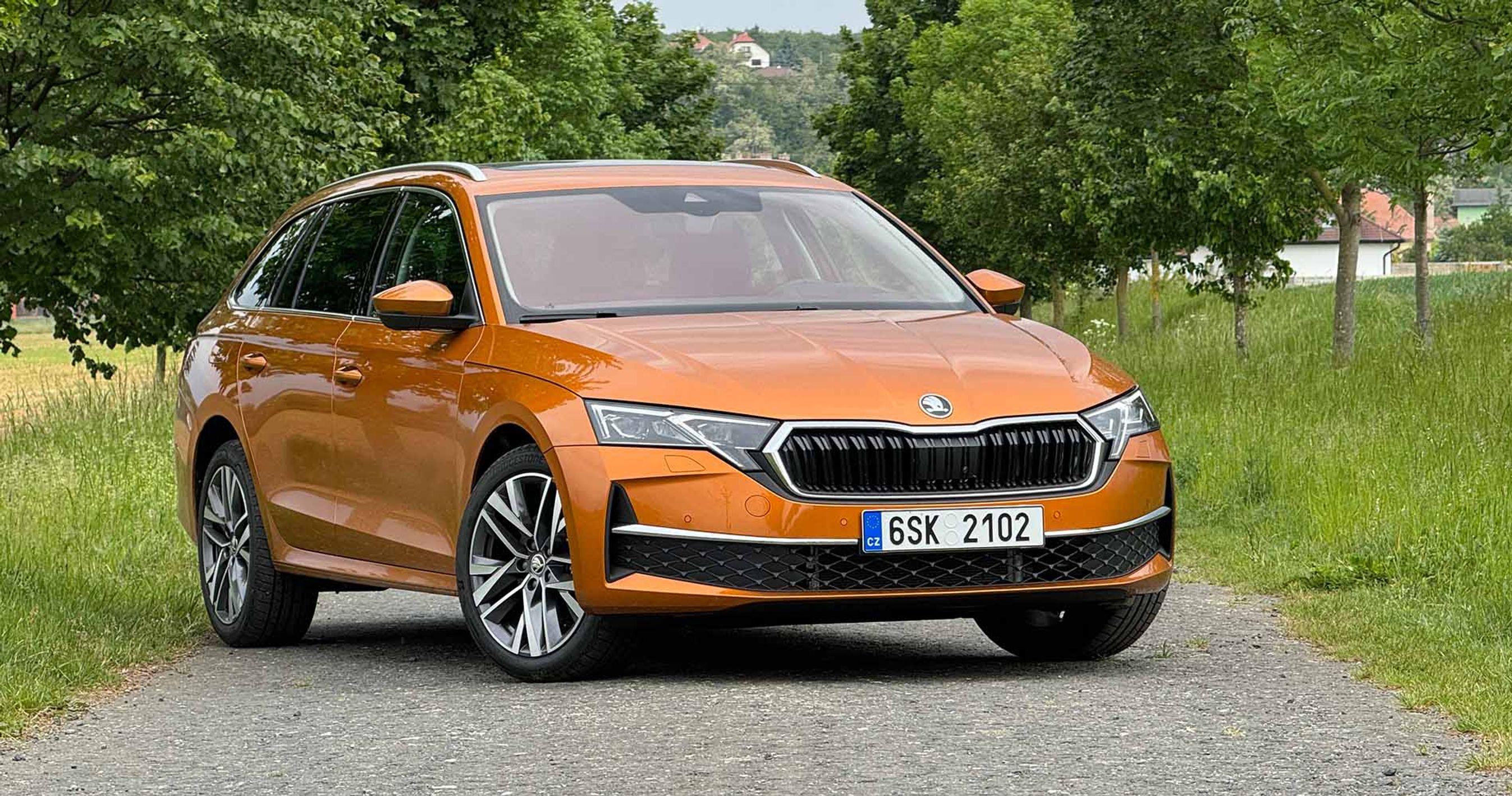En orange Skoda Octavia holder på en vej med træer i baggrunden