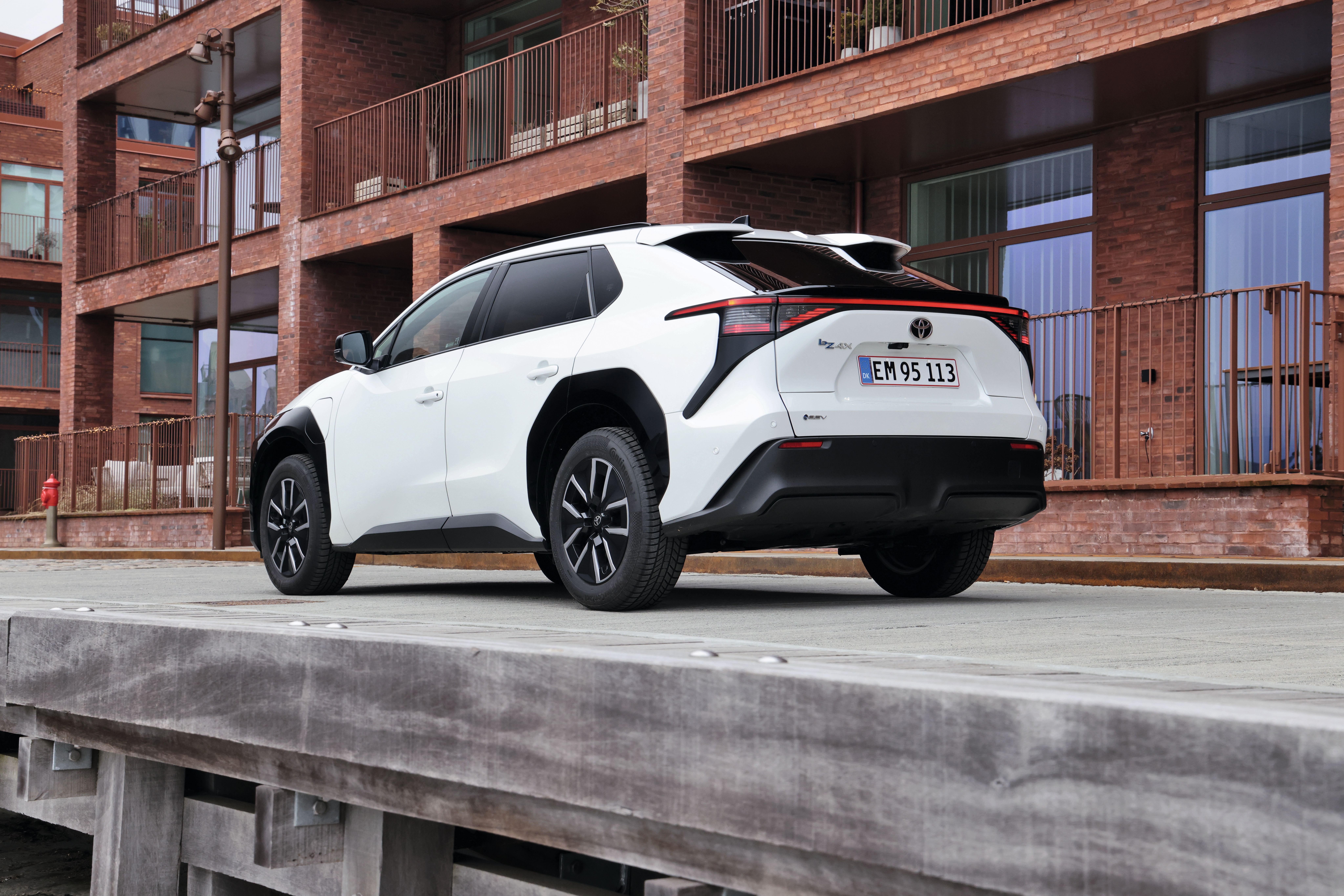 Toyota bZ4X set bagfra med rød bygning i baggrunden