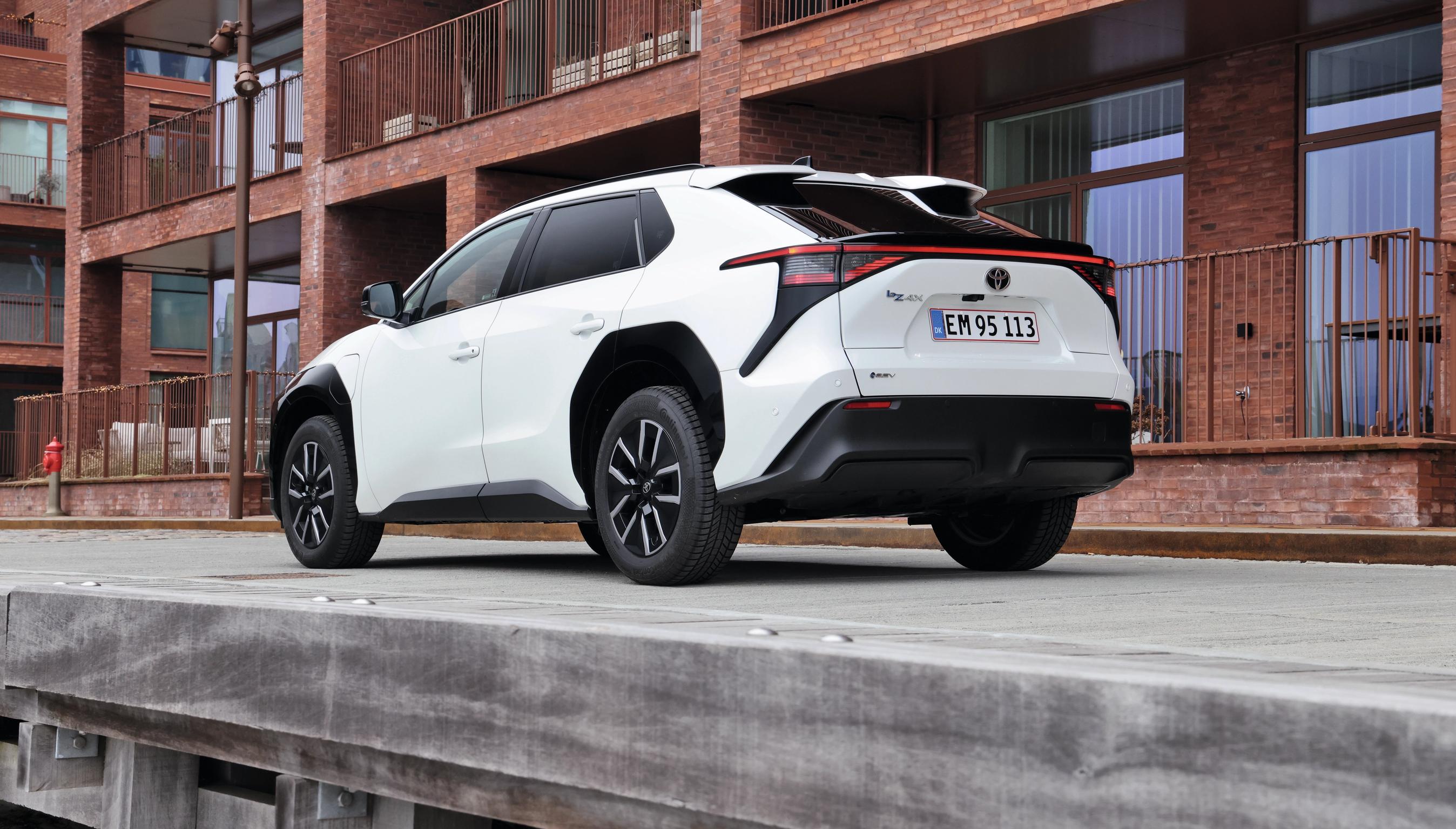 Toyota bZ4X set bagfra med rød bygning i baggrunden