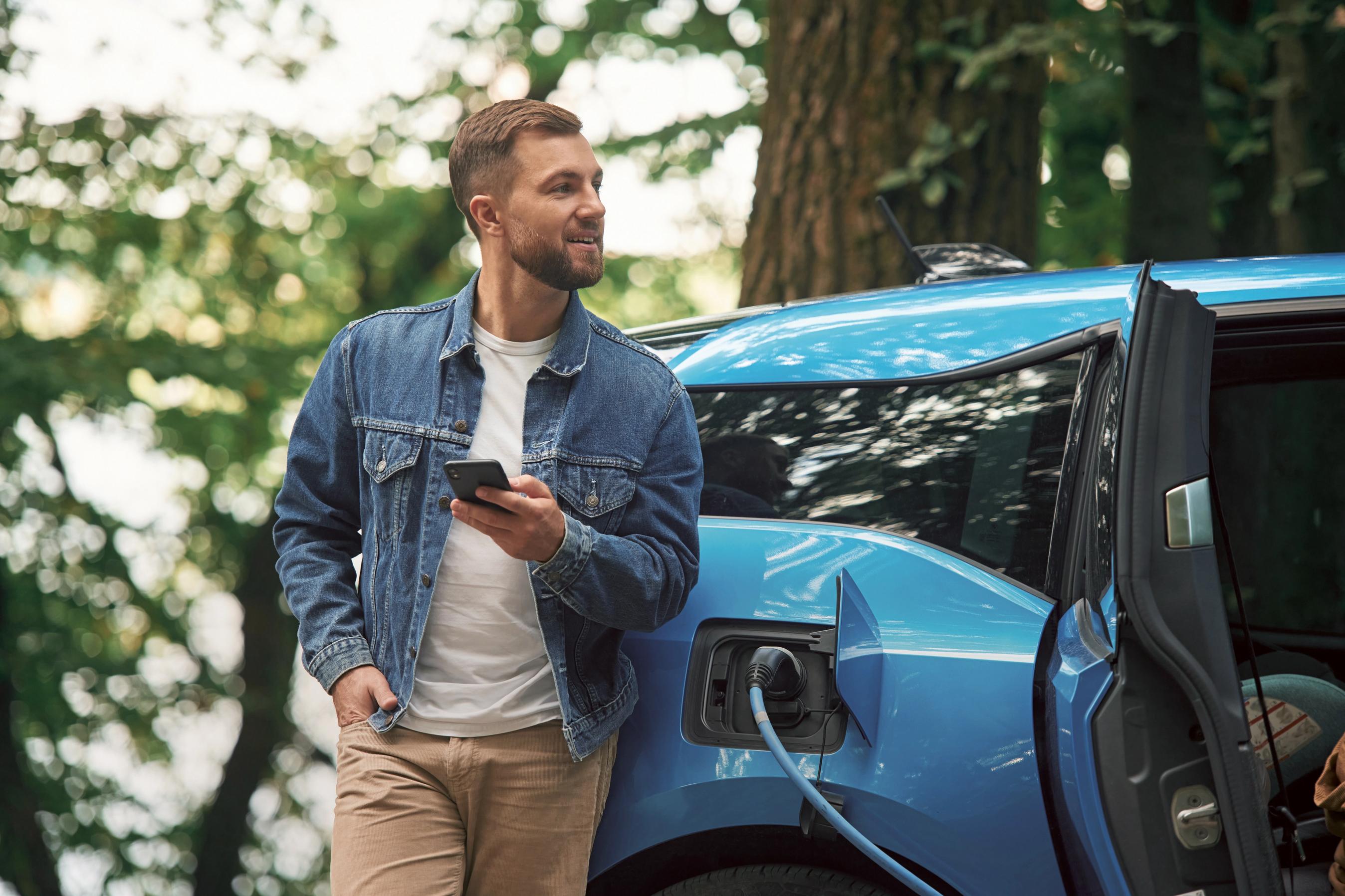 Mand står i en skov og lader hans bil op