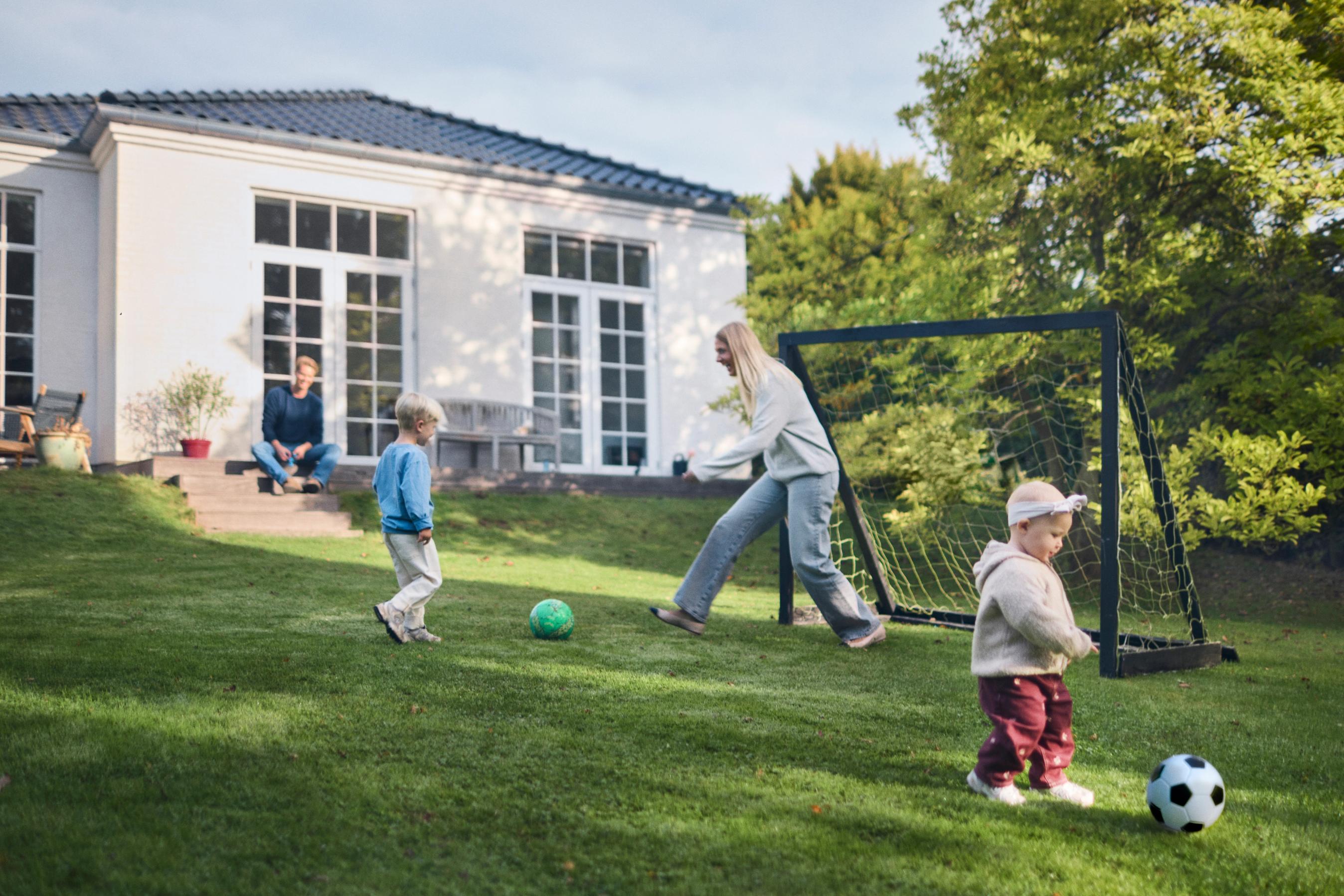 To børn spiller fodbold i en have