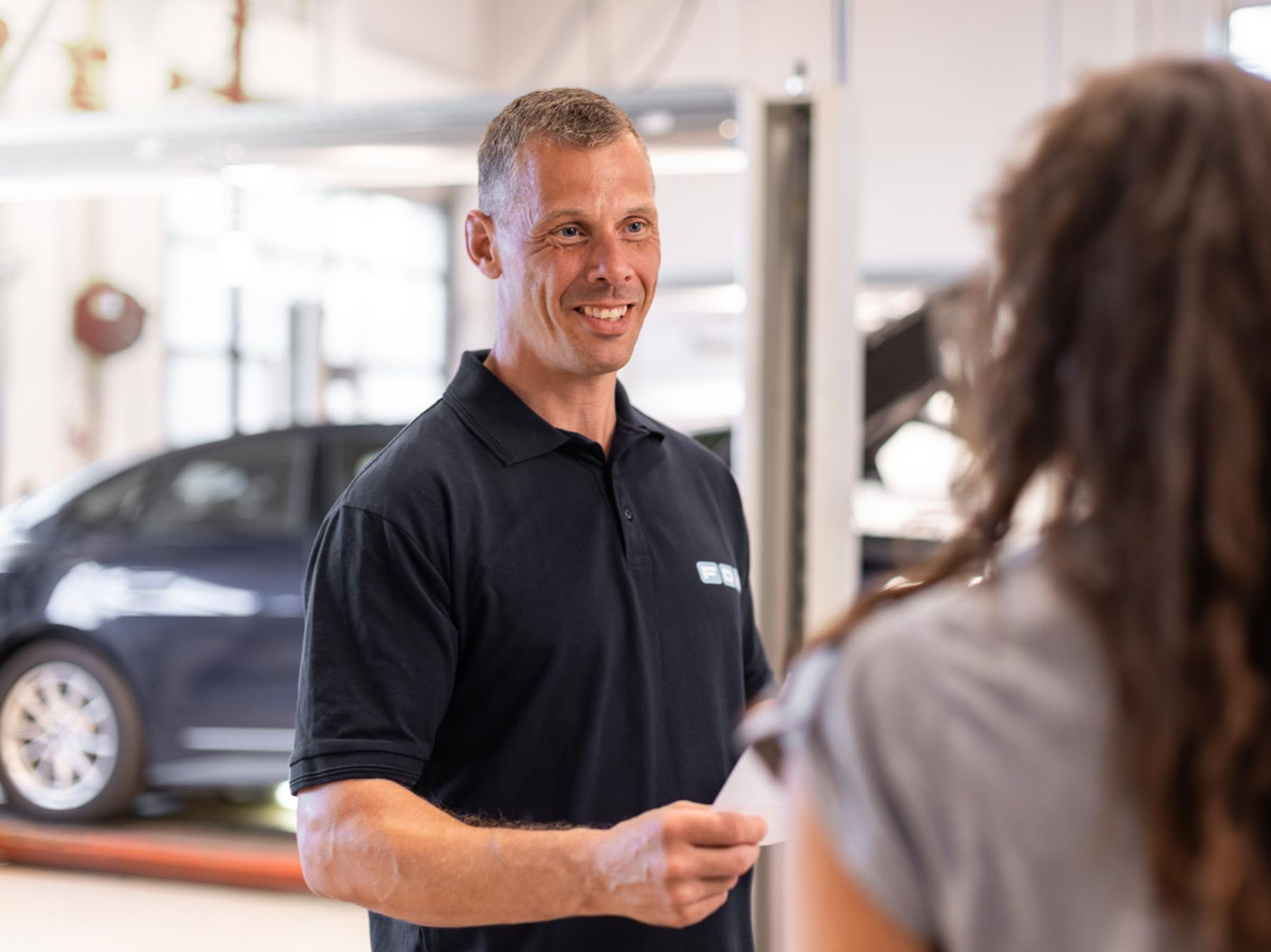 Medarbejder hos FDM afleverer synsrapport til kunde med bil på testcenteret