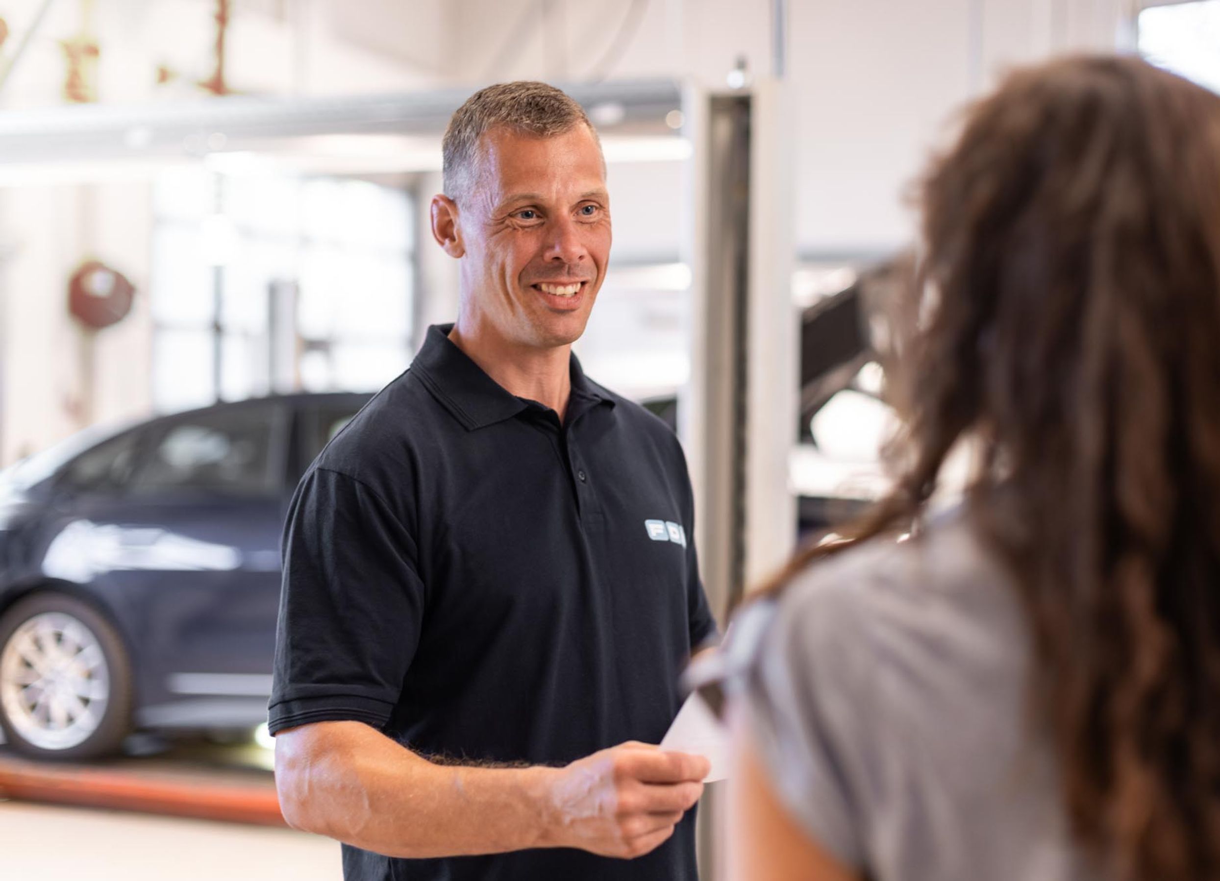 Medarbejder hos FDM afleverer synsrapport til kunde med bil på testcenteret