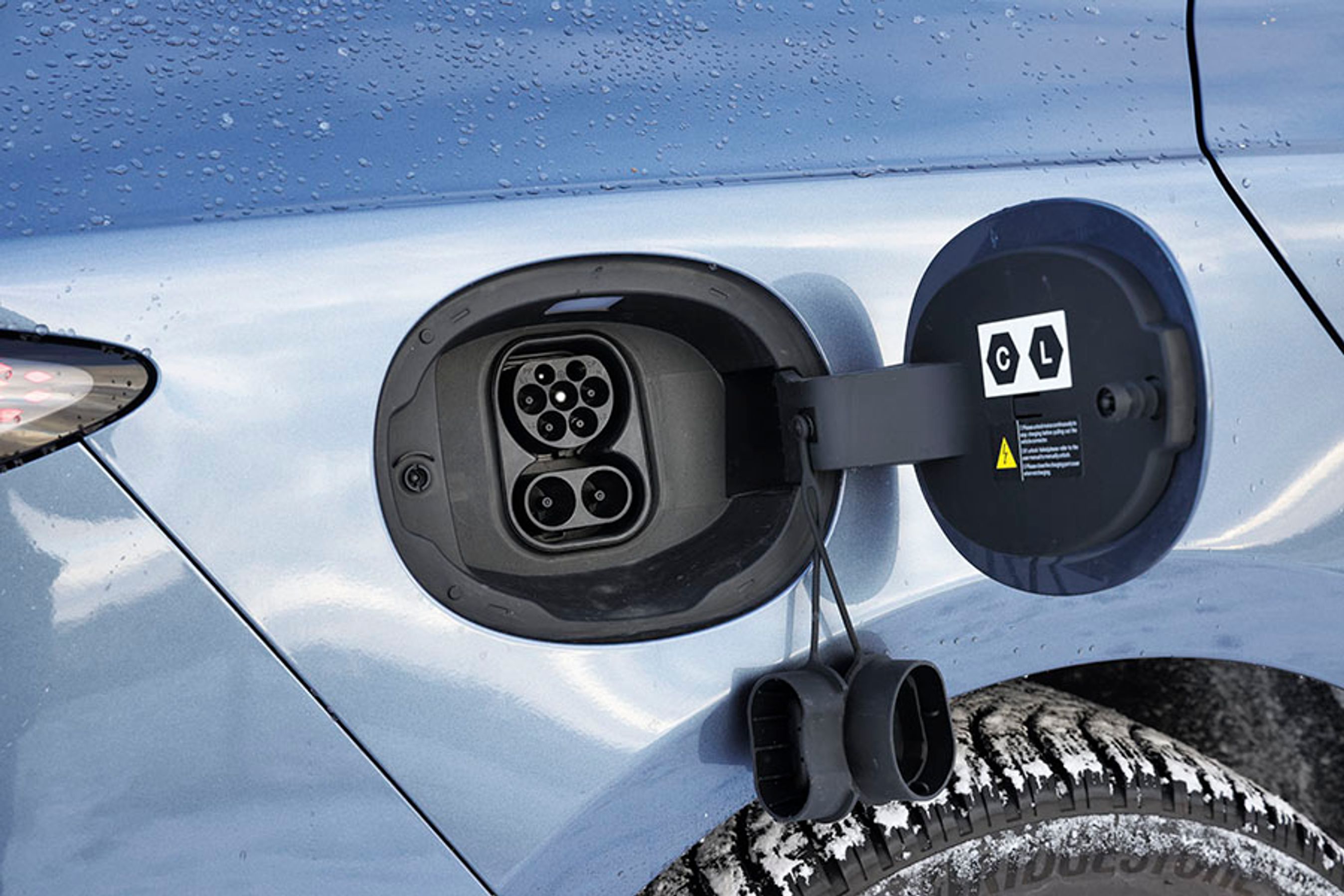 Ladelugen er placeret ved højre baghjul. På farten kan man DC-lade med op til 150 kW, og hjemme kan man lade med 11 kW. De to gummipropper er en generende detalje i hverdagen.