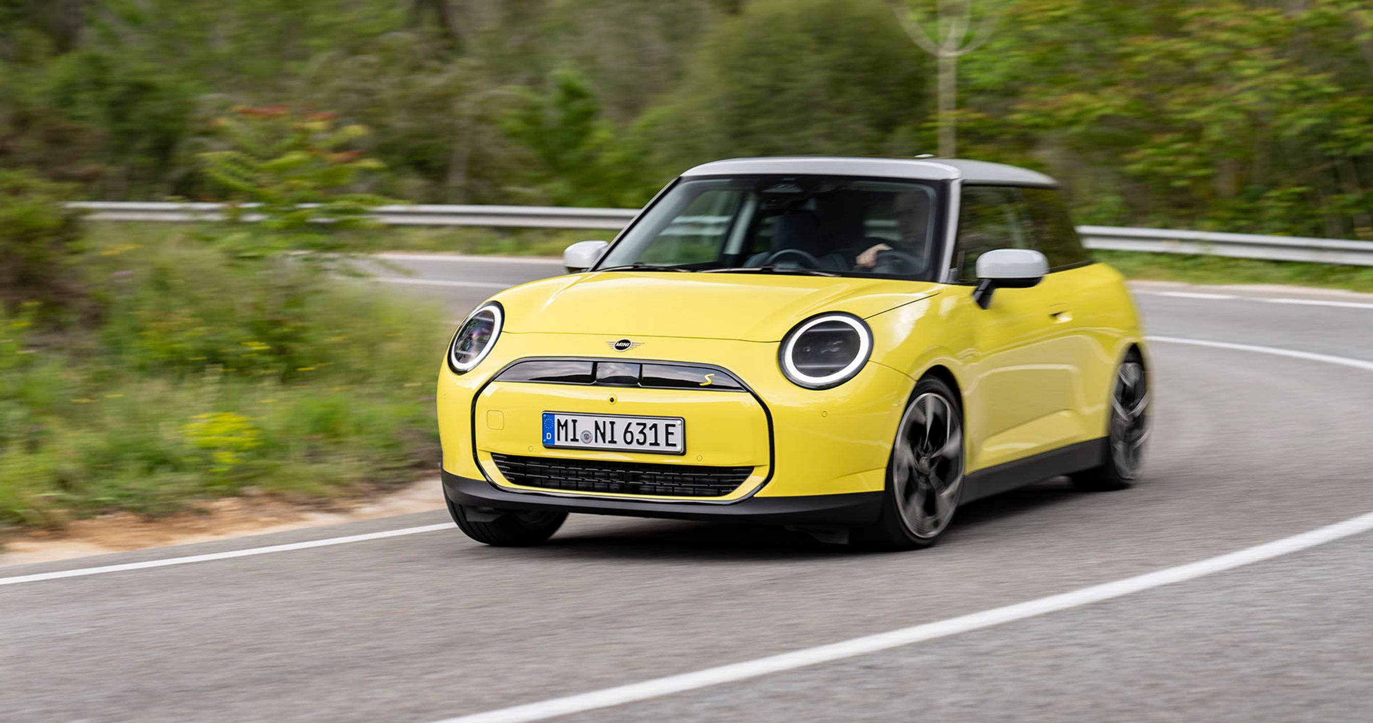 Gul Mini Cooper kører i et sving på en vej