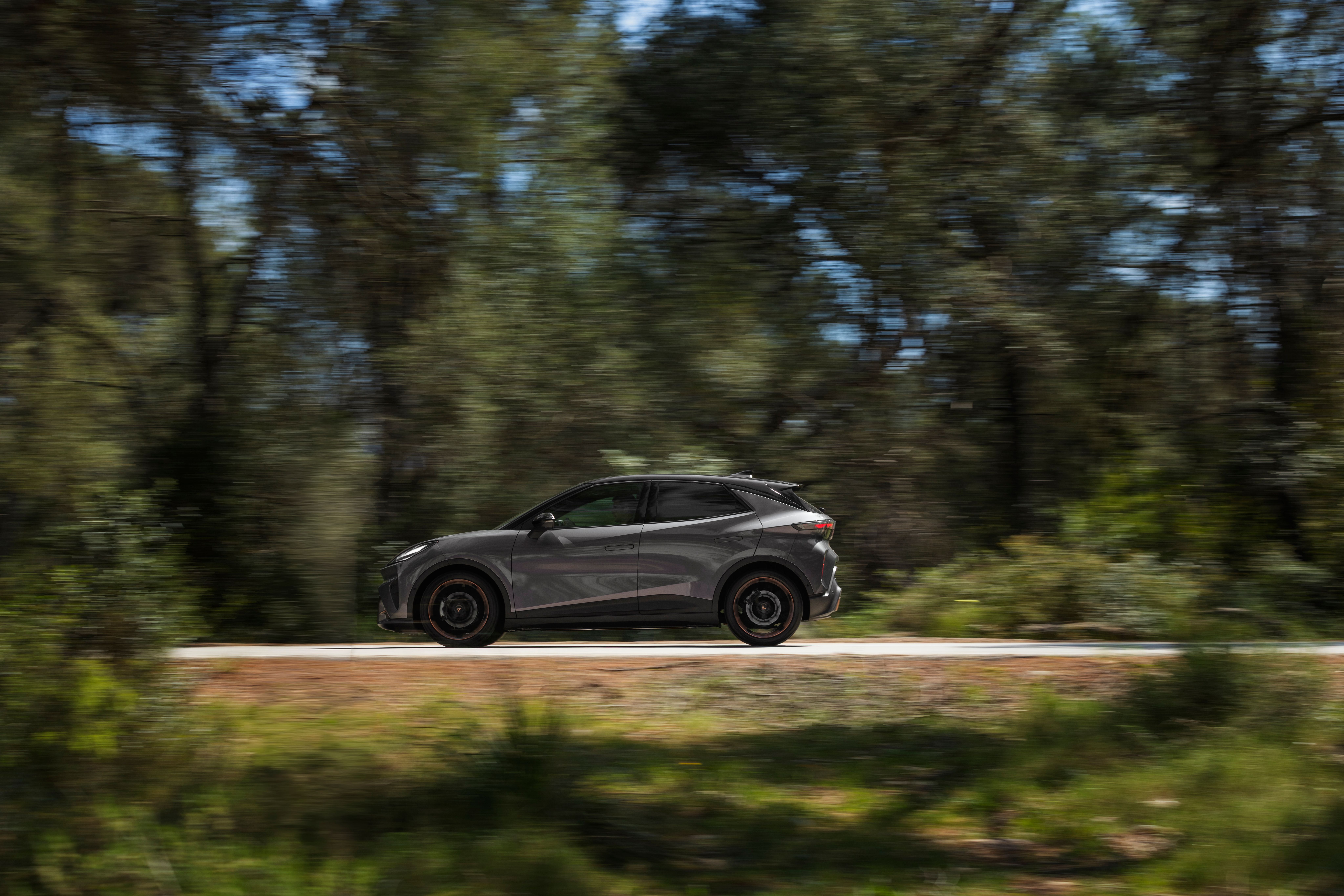 Cupra Raval VZ Extreme 2026 set fra siden kørende på en landevej med skov i baggrunden. 