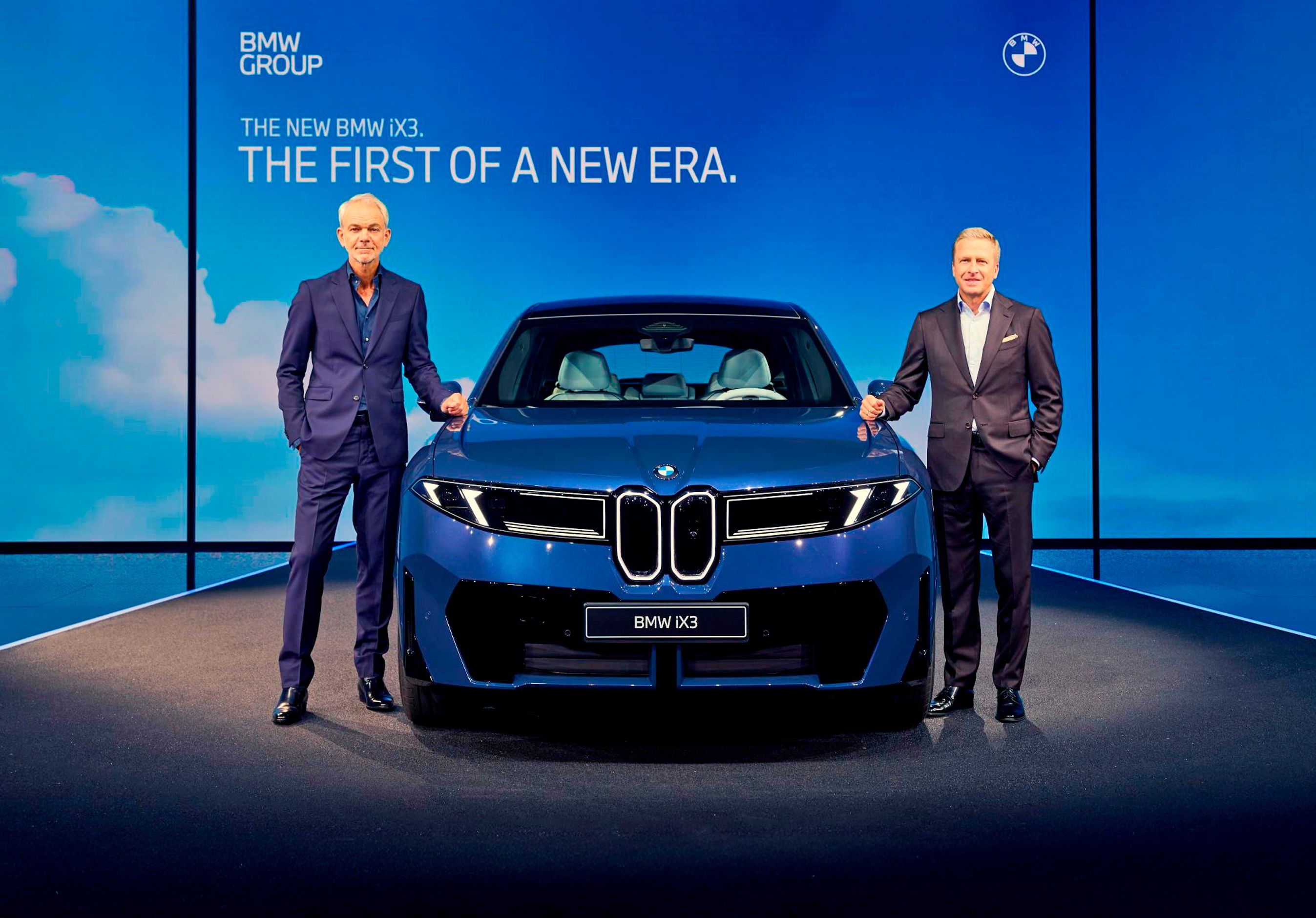 To mænd ved blå bil set forfra.