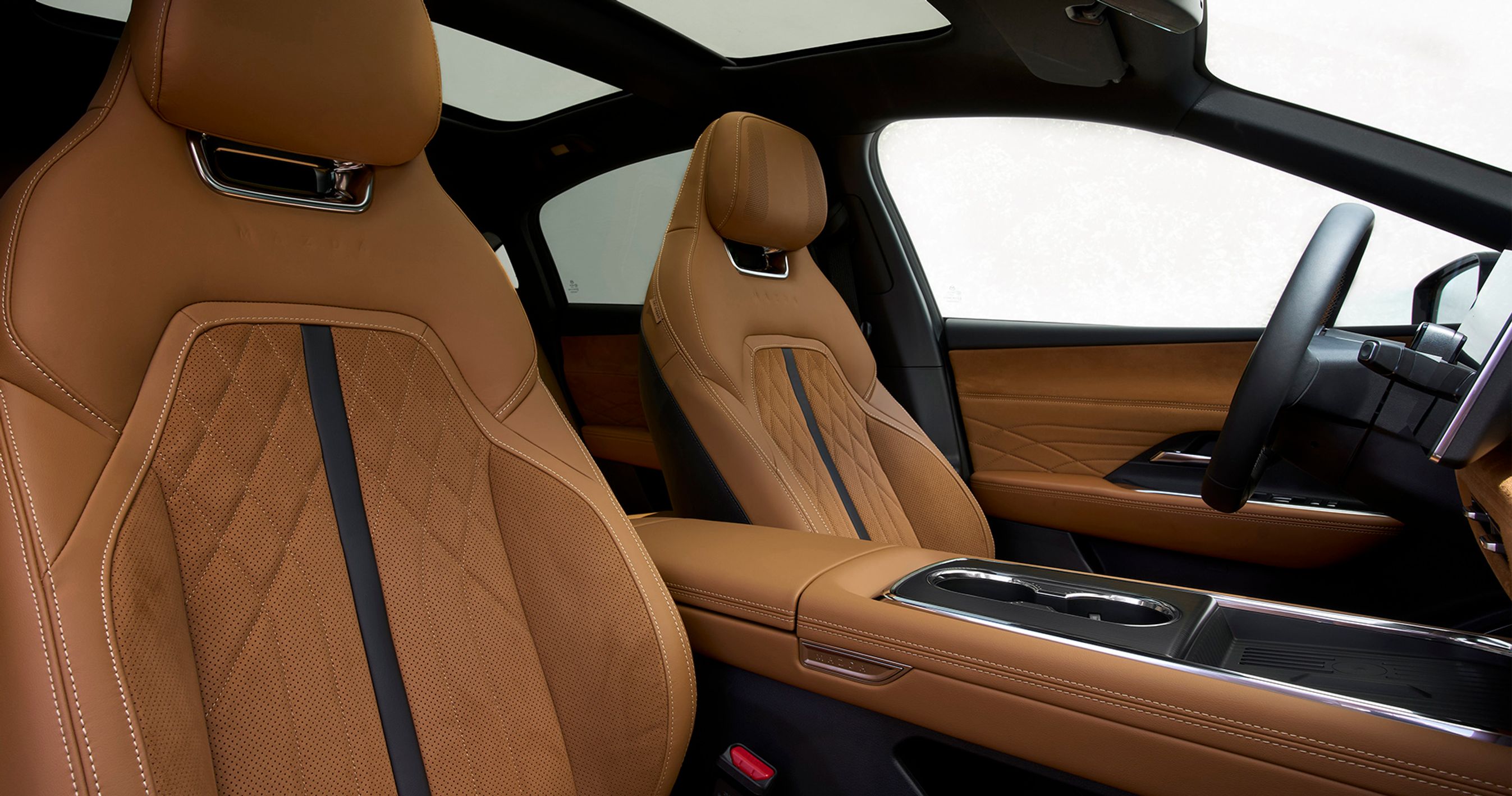 Forsæderne er i topudgaven som her betrukket med læder og ruskind i denne brune farve. I grundudgaven er der kunstlæder med valg mellem en lys hvid eller sort kabine. Glastag er standard, og i topudgaven er der et elektrisk betjent undertag.