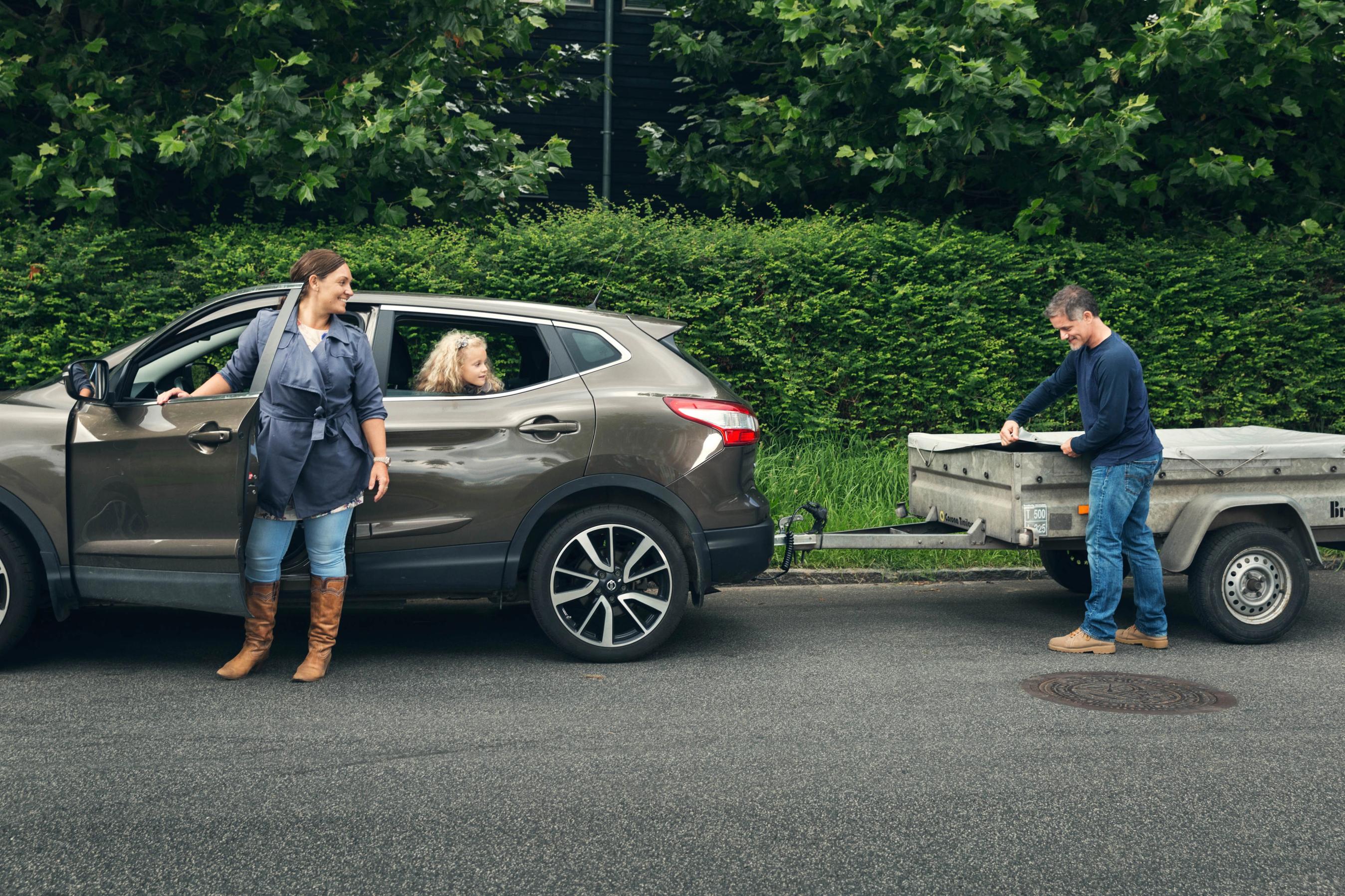 Mand er ved at pakke trailer, mens kvinde er klar til at køre bilen.