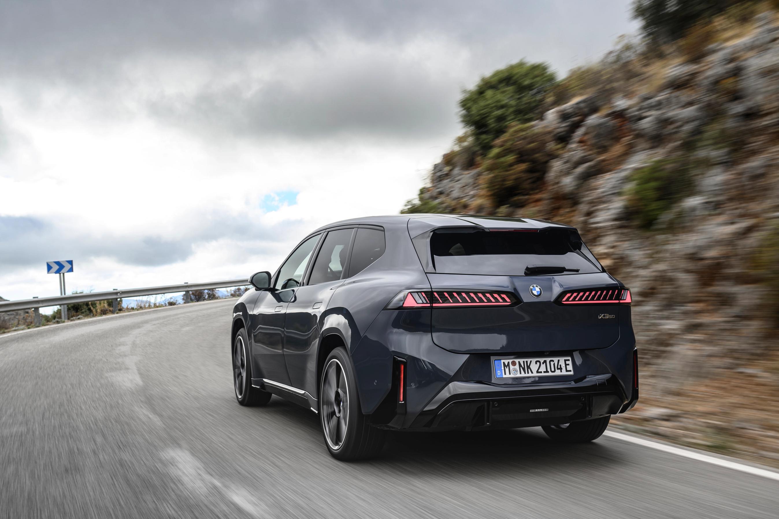 BMW iX3 set bagfra, mens den kører i et sving på en bjergvej