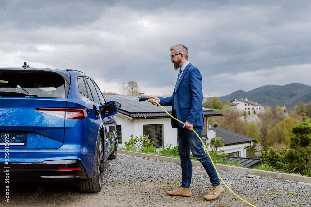 Mand sætter oplader i bilen hjemme