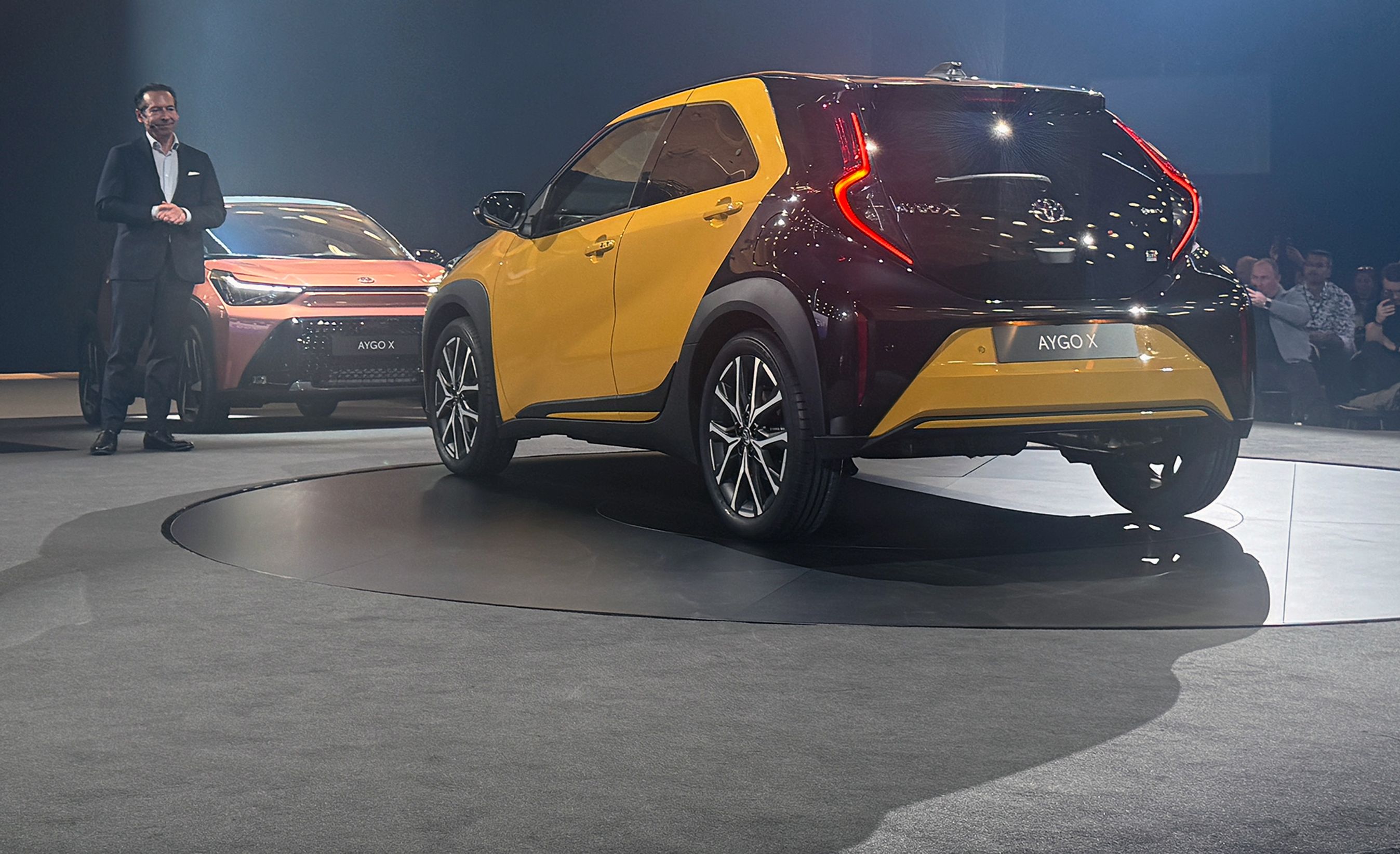 Gul Toyota Aygo X bagfra på scene.