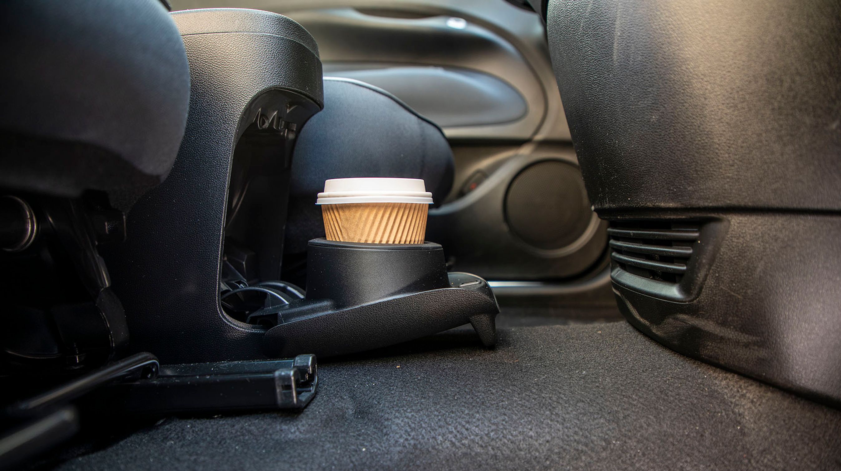 Der er en flaskeholder i det midterste opbevaringsrum, mens en kaffekop skal placeres i en holder, der kan vippes frem mellem forsæderne.