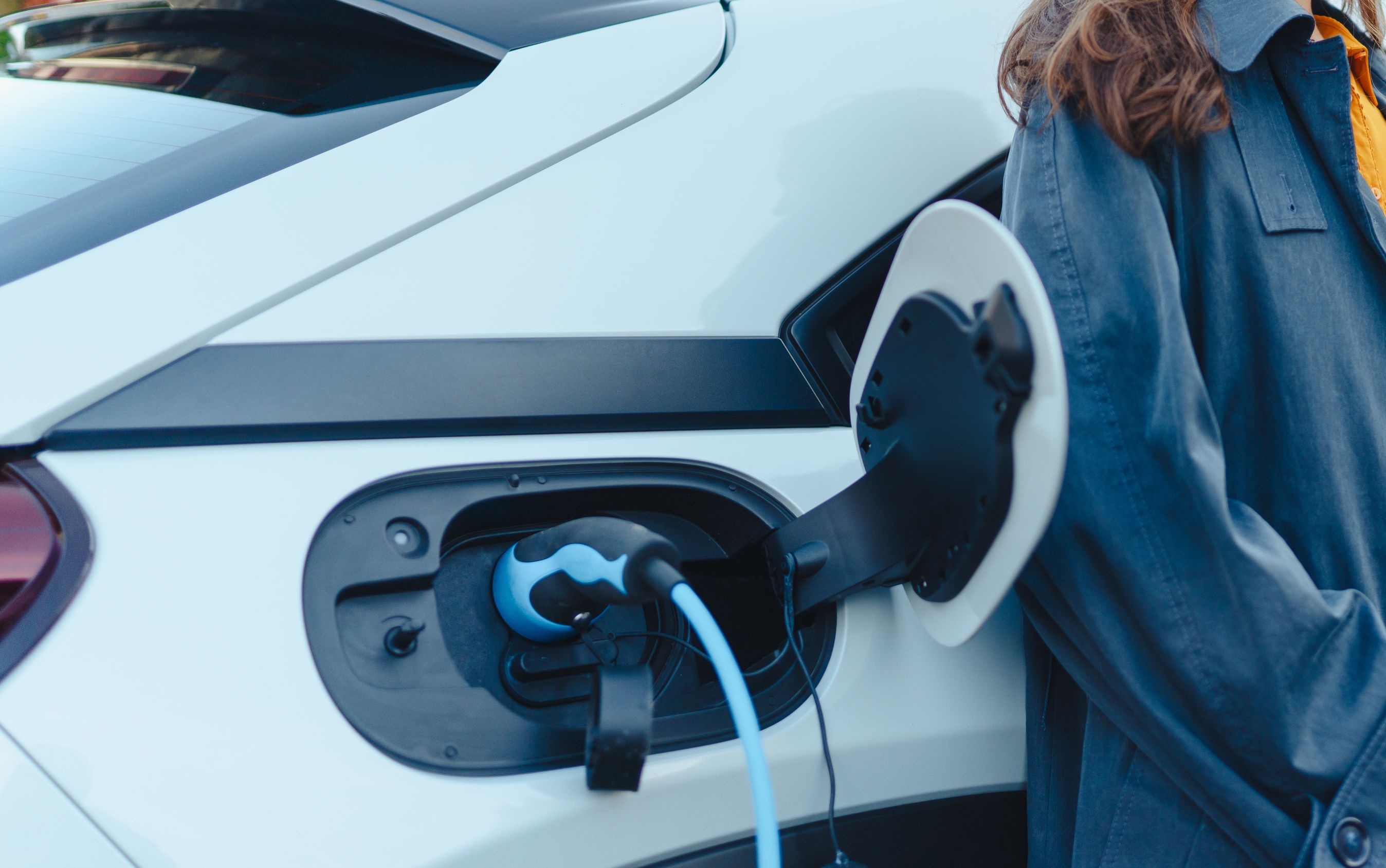 kvinde står op af en elbil mens den lader