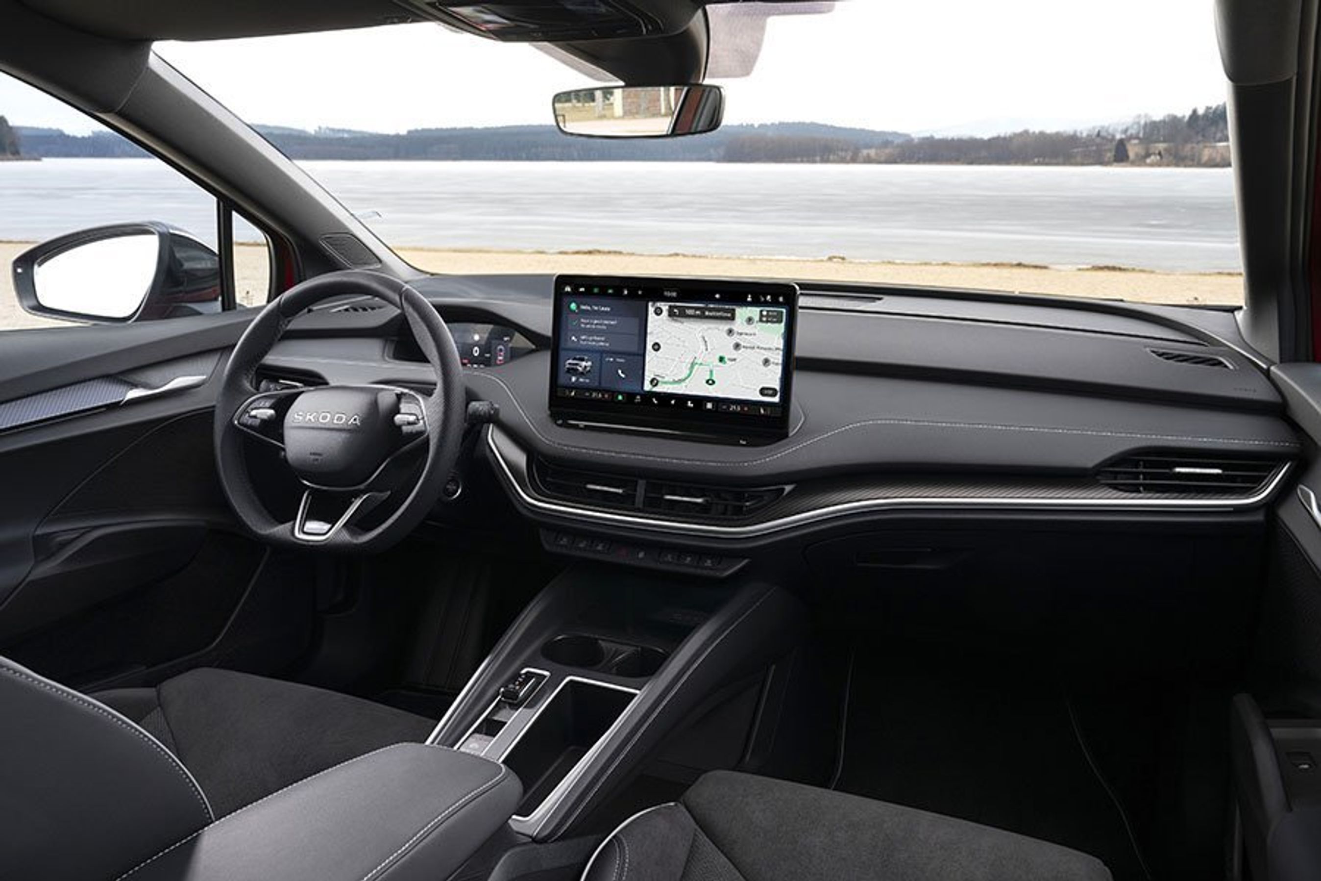 Førerpladsen i en Skoda Enyaq med sø set ud af forruden
