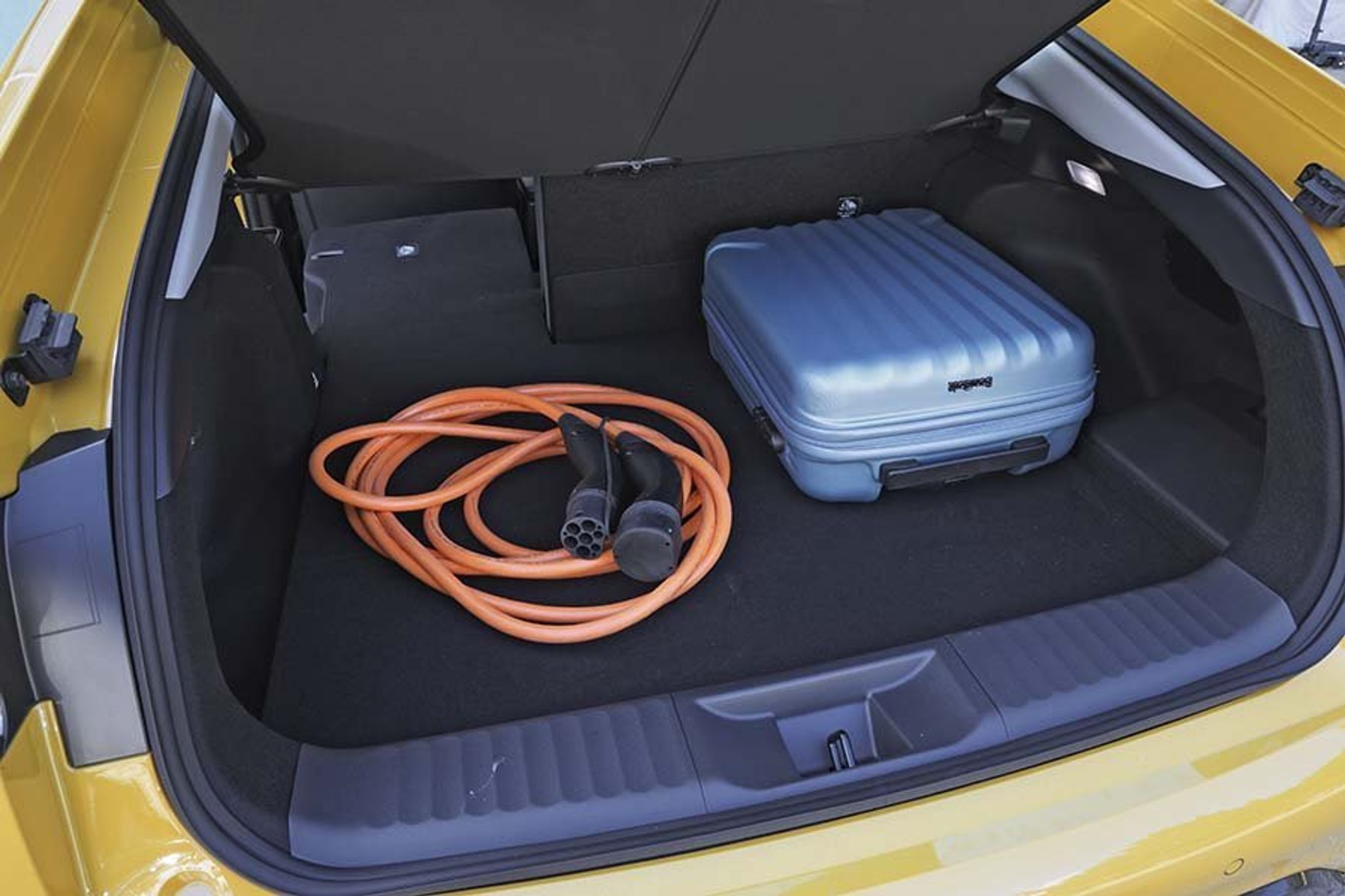 Bagagerummet i en Toyota Prius med blå kuffert og ladekabel.