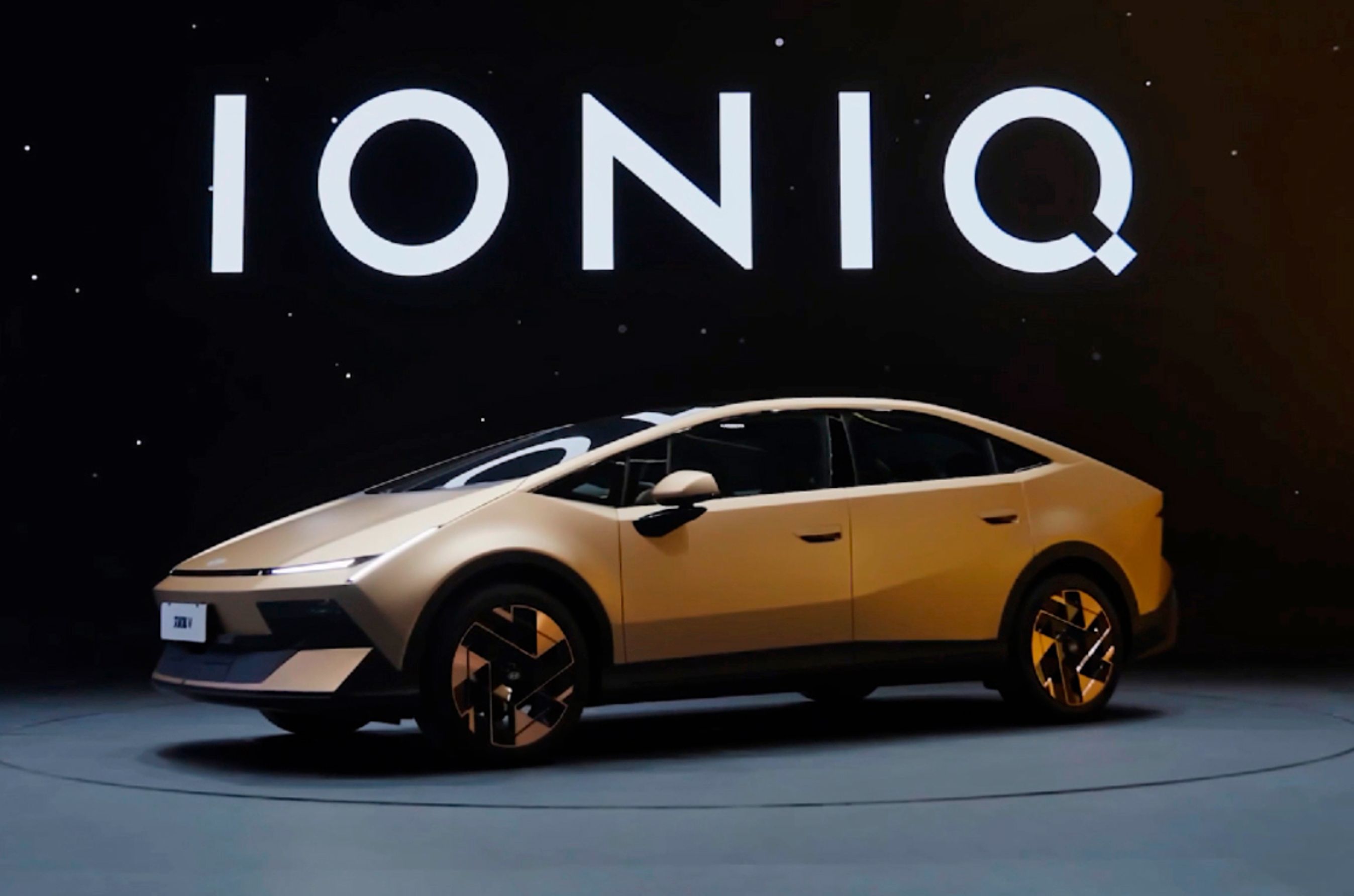 Guldfarvet Hyundai Ioniq V på sort scene.