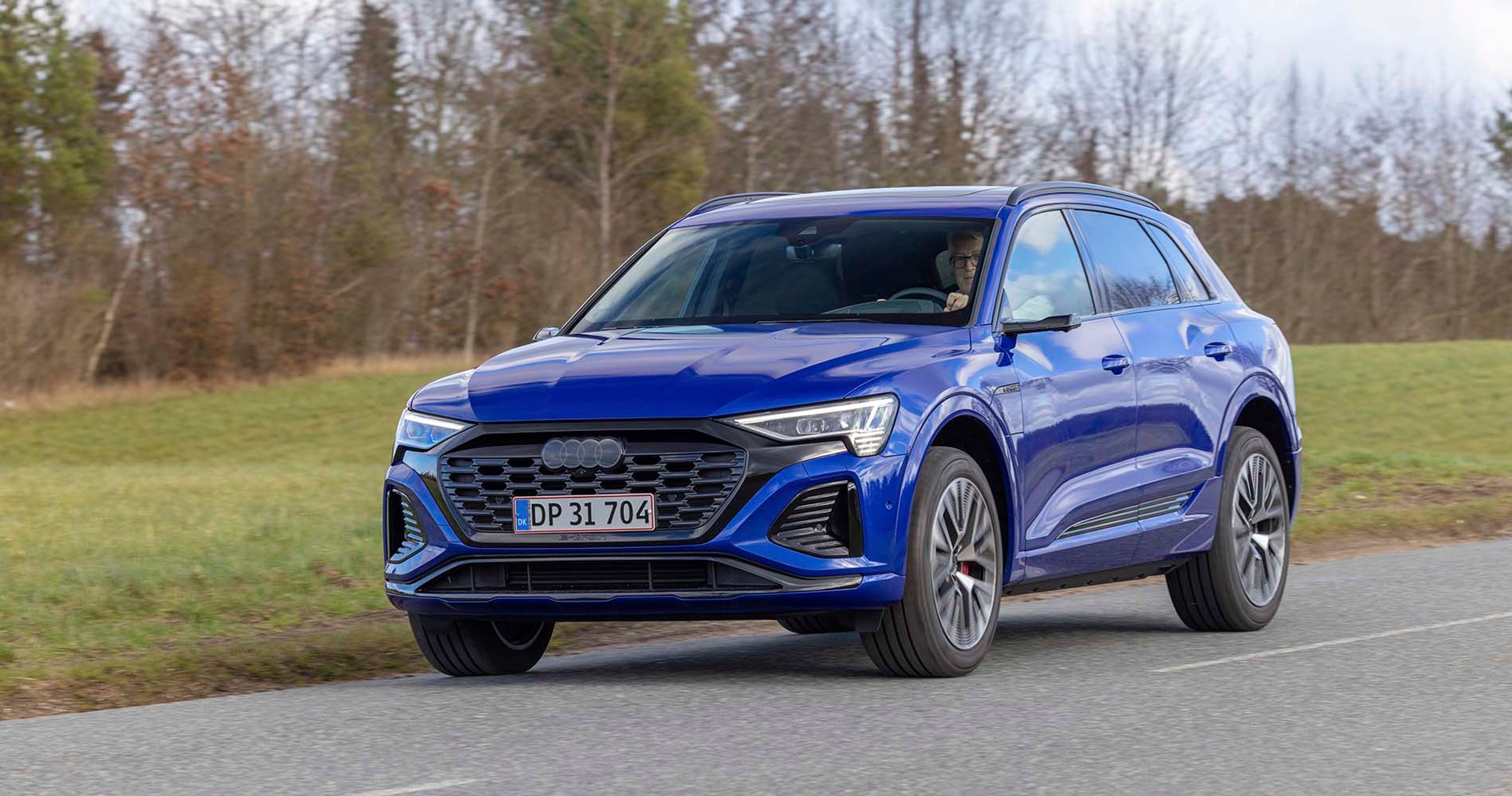 Elbilen Audi Q8 kører på landevej med græs i baggrunden