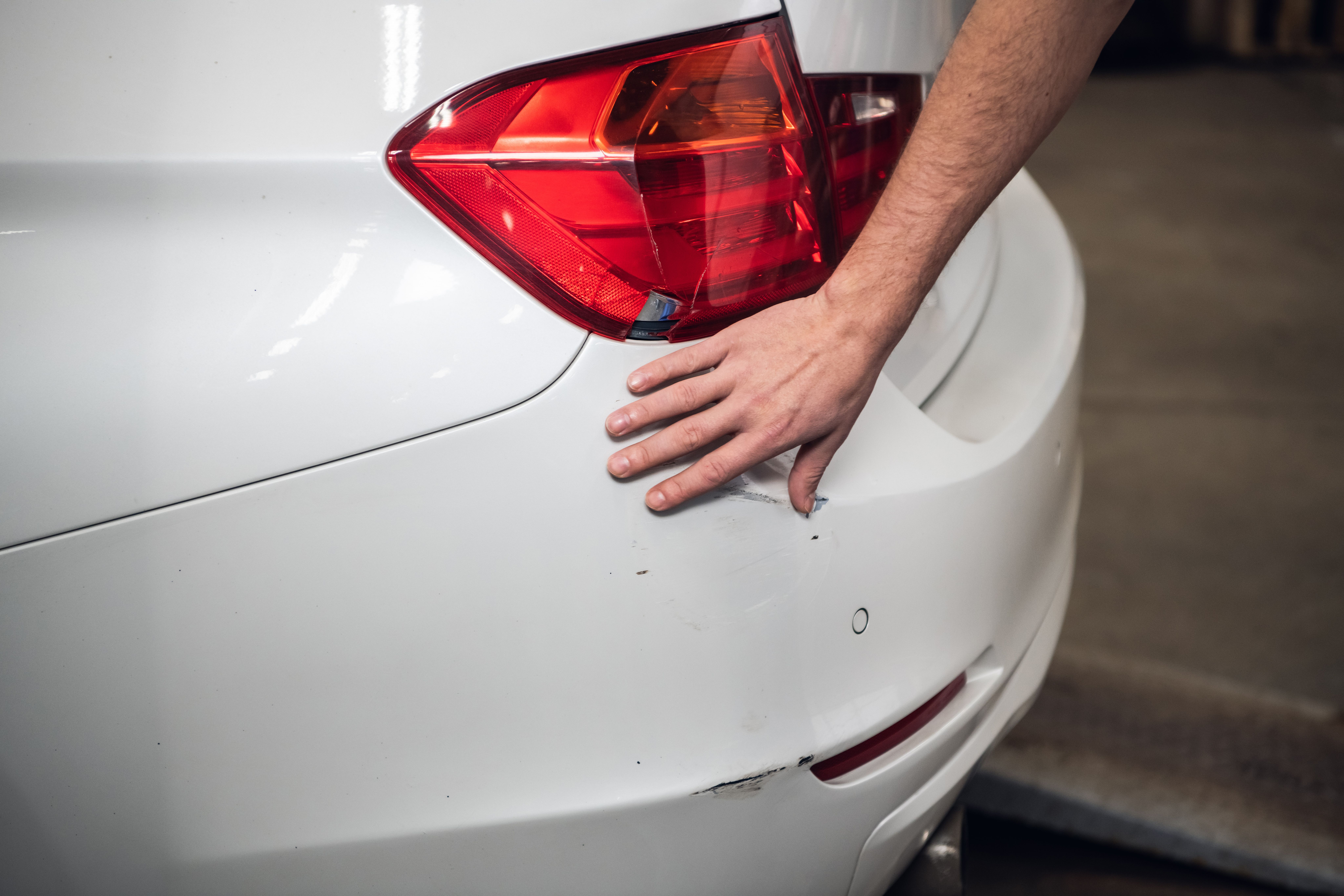 Skade på bagkofangeren på en hvid bil.