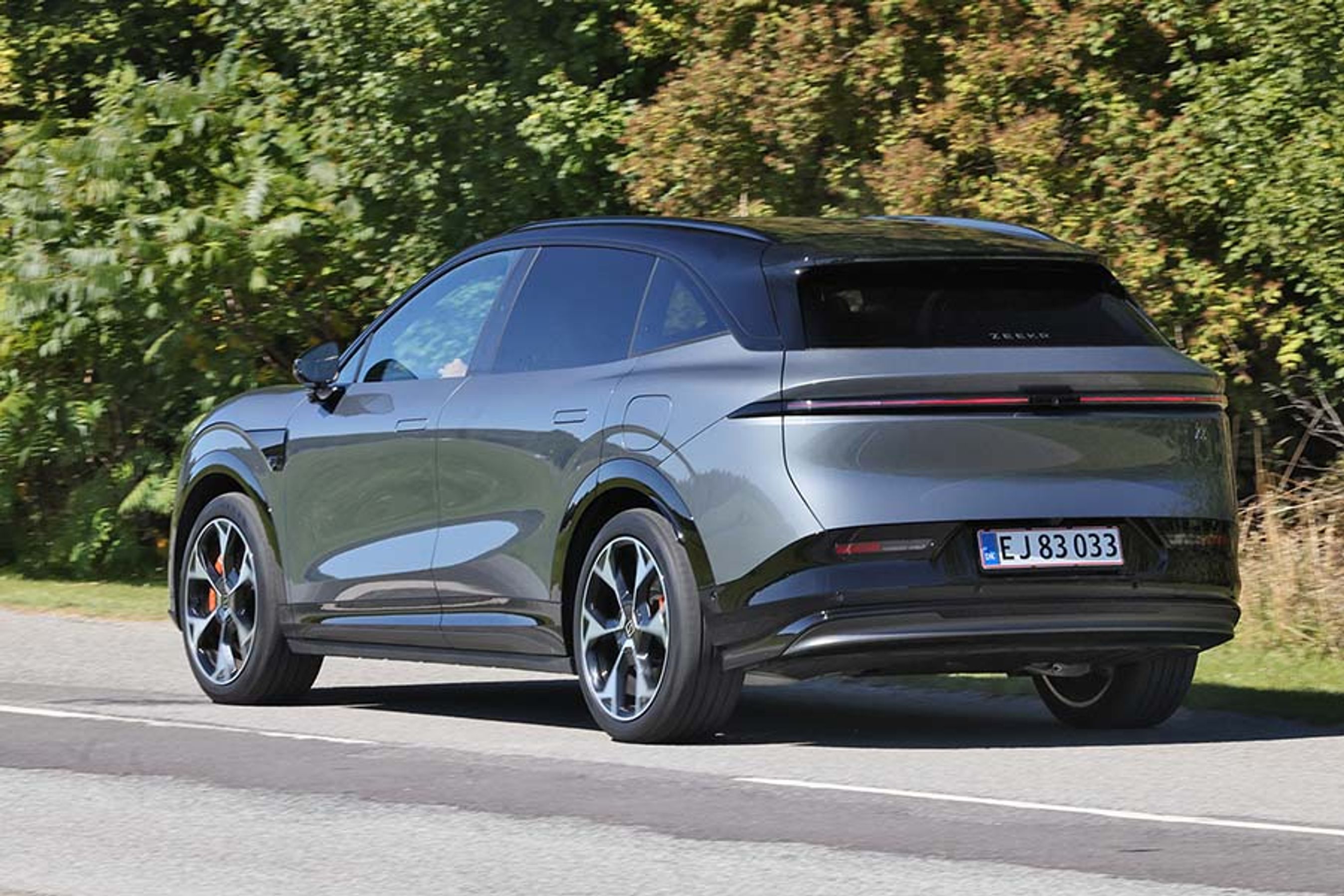 Zeekr 7X set bagfra, mens den kører foran træer