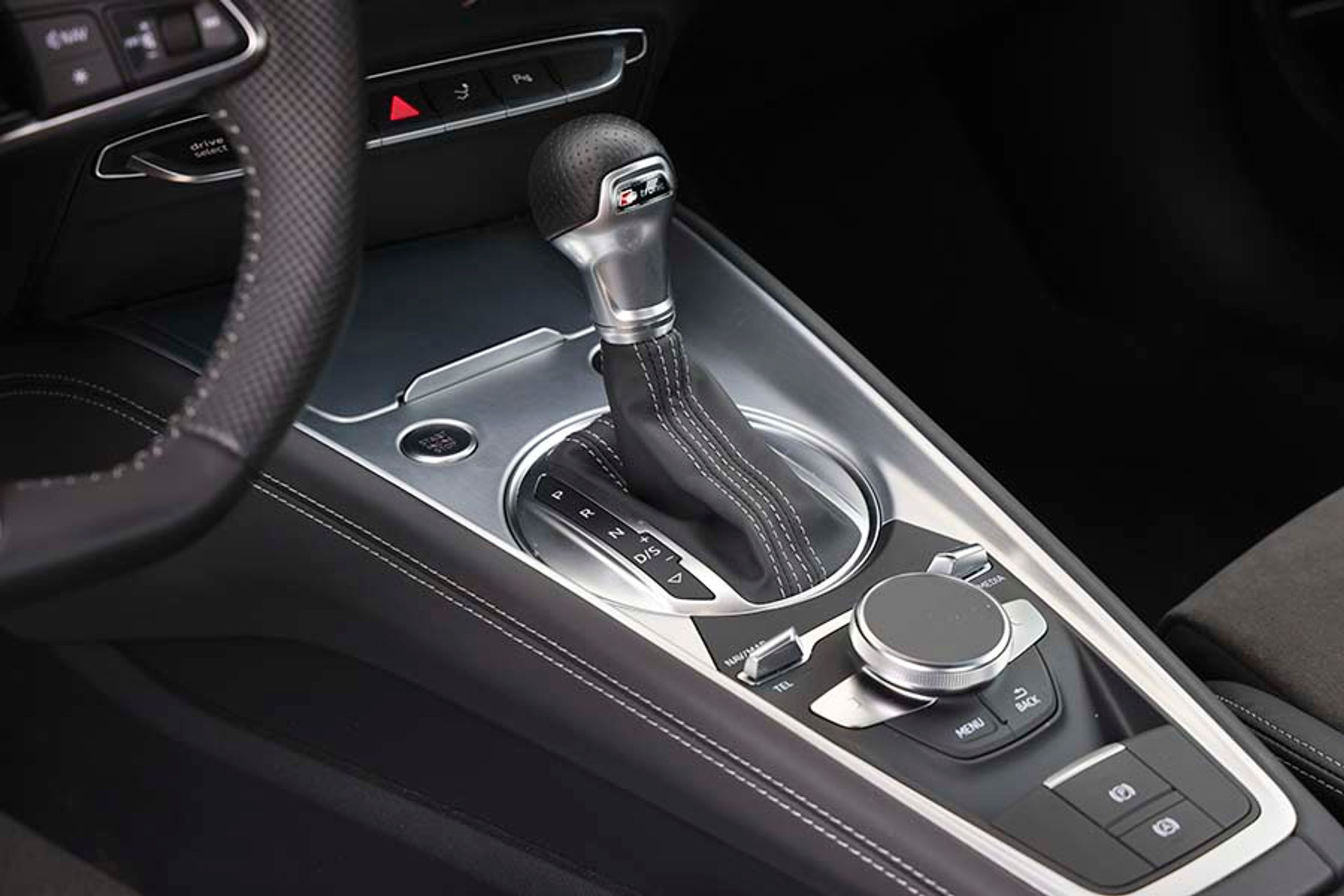 Gearvælgeren til dobbelkoblingsgearkassen er af den klassiske type, hvor du skal flytte gearvælgeren fysisk. Der er dog en start/stop-knap lige foran til venstre. Den store drejeknap er til at betjene menuen i instrumentskærmen. 