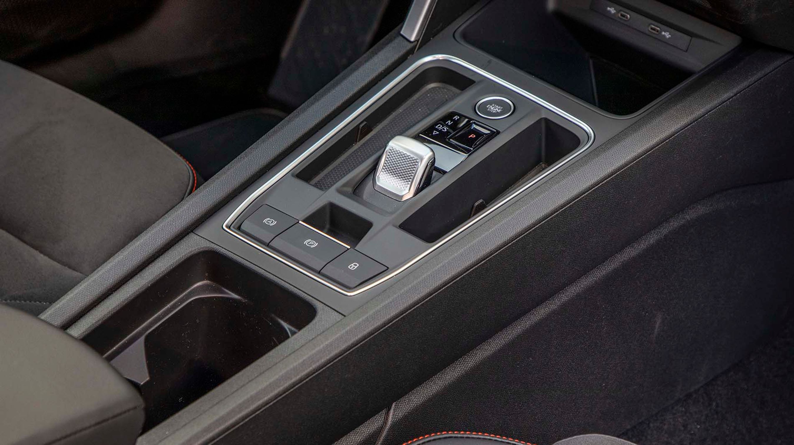 Mellem forsæderne er der placeret en diminutiv gearvælger af den elektroniske type, der selv går i P, når turen er slut. Der er desuden fine opbevaringsrum.